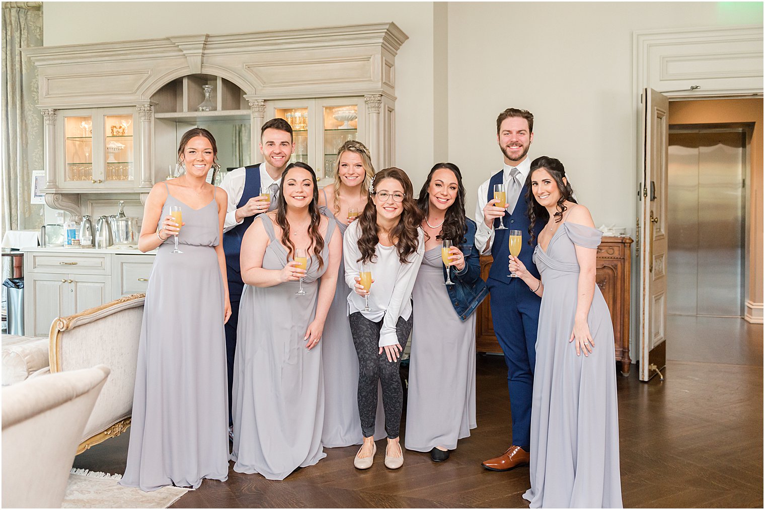 bride poses with bridal party holding champagne at Park Chateau Estate and Gardens
