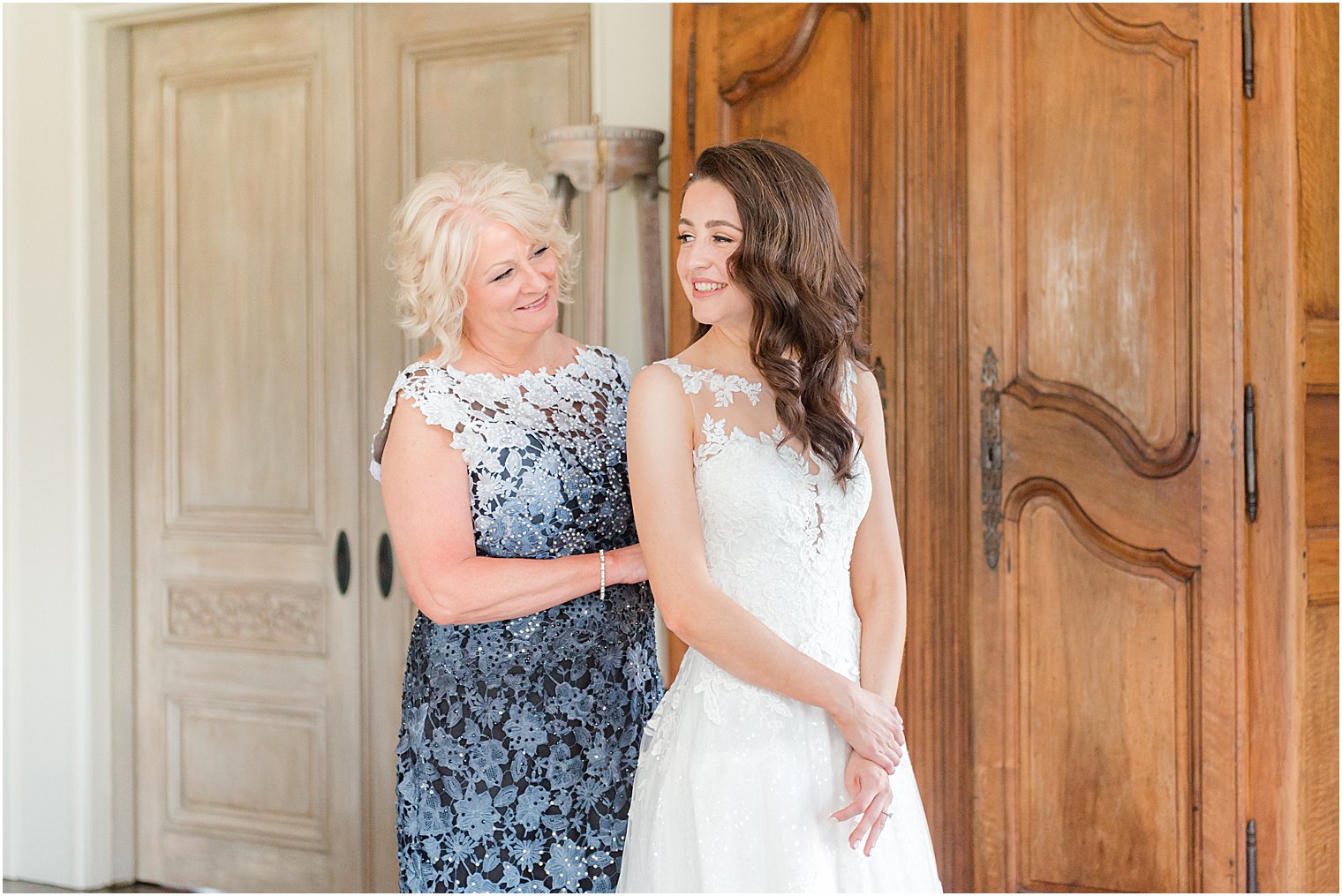 mother helps bride into wedding dress at Park Chateau Estate and Gardens