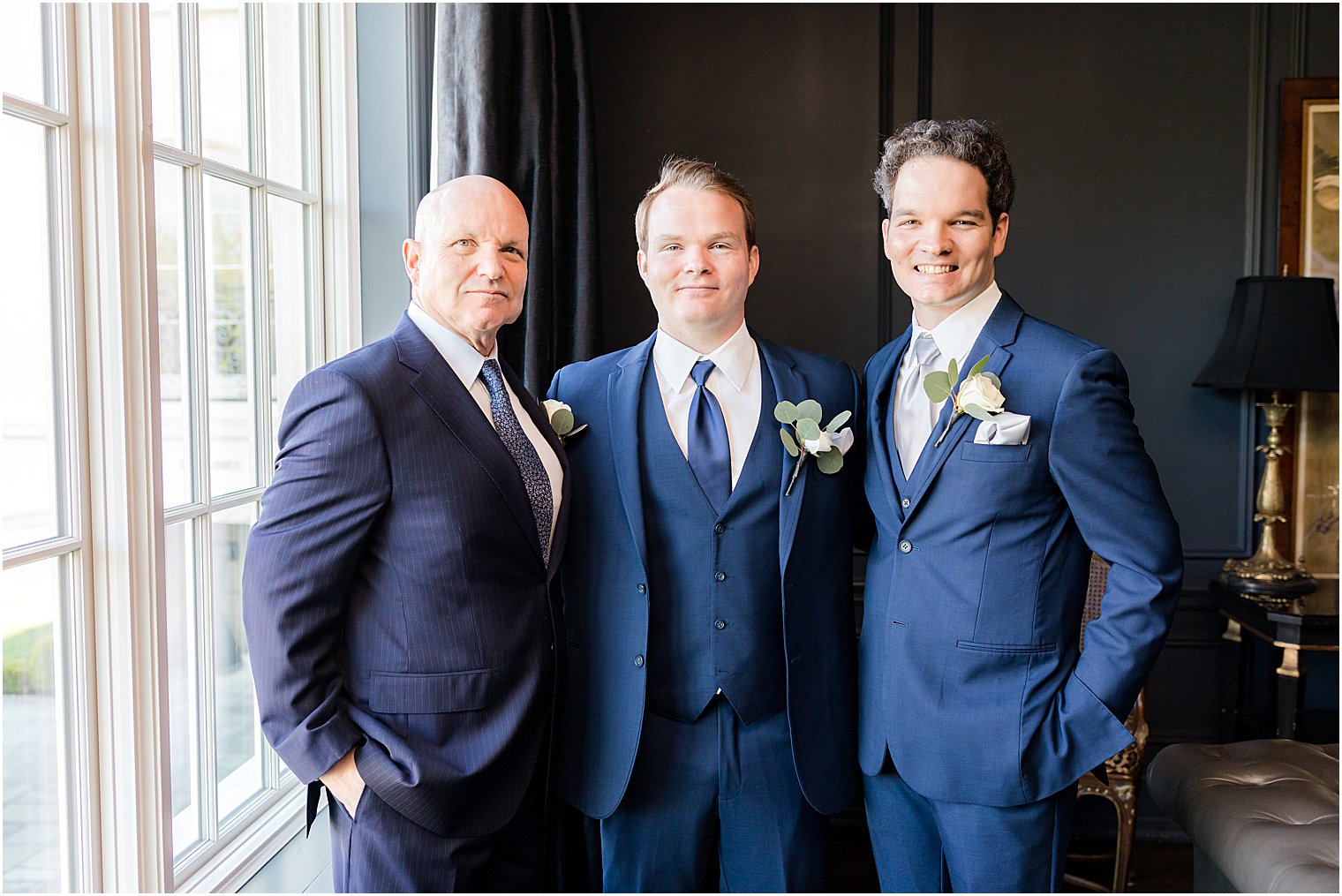 groom poses with brother and dad by window at Park Chateau Estate and Gardens
