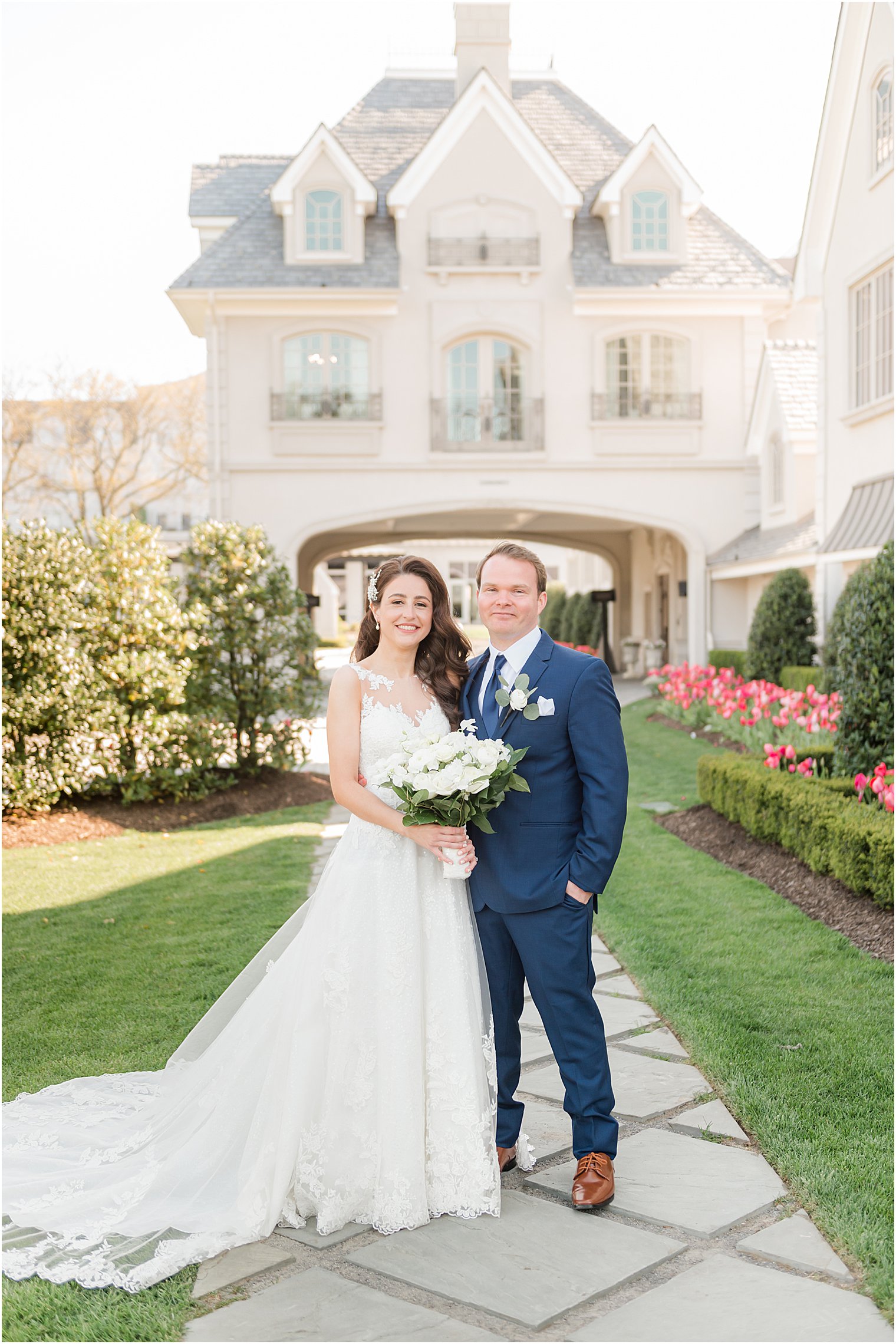 bride and groom stand in front of estate house at Park Chateau Estate and Gardens