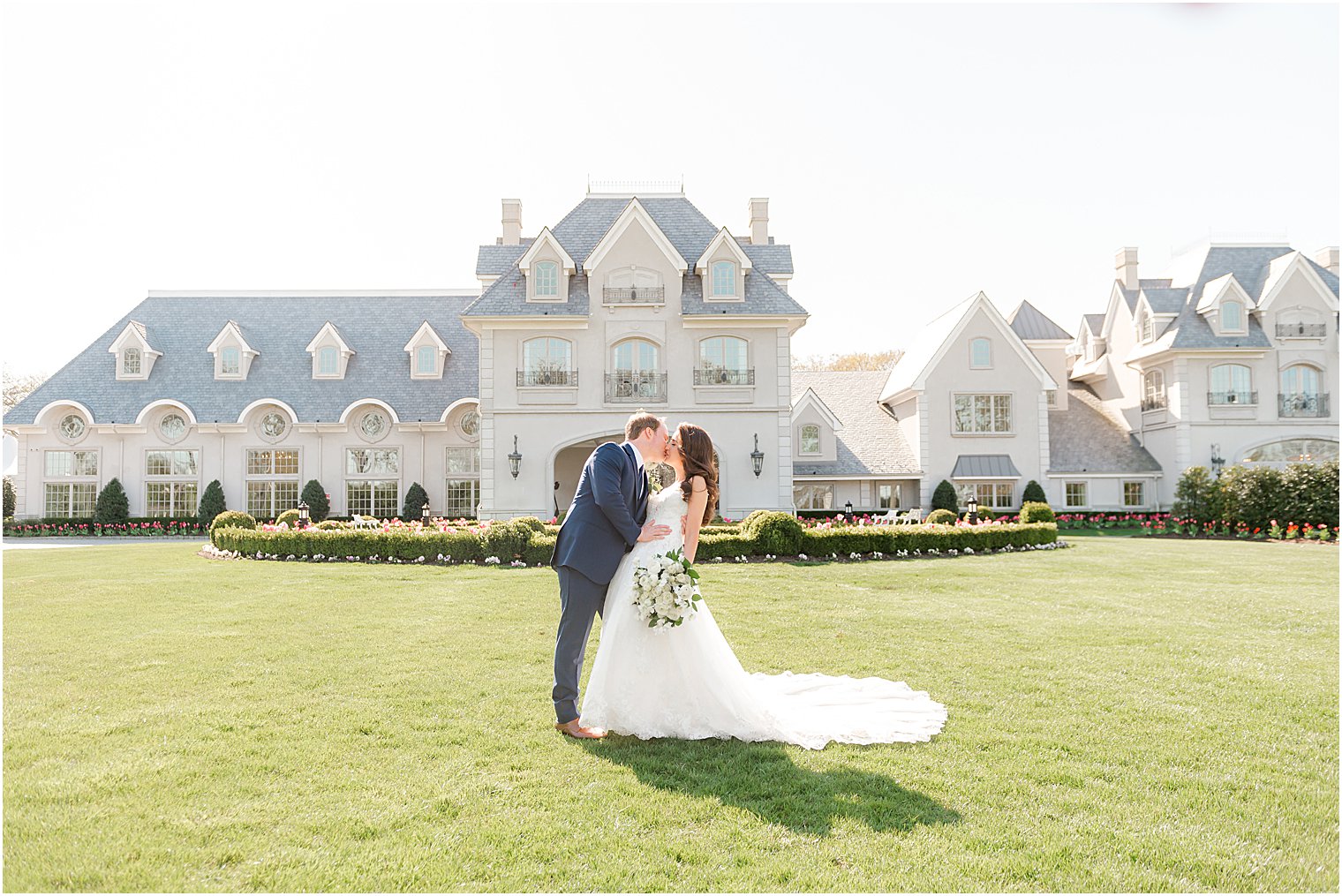 bride and groom kiss on lawn at Park Chateau Estate and Gardens