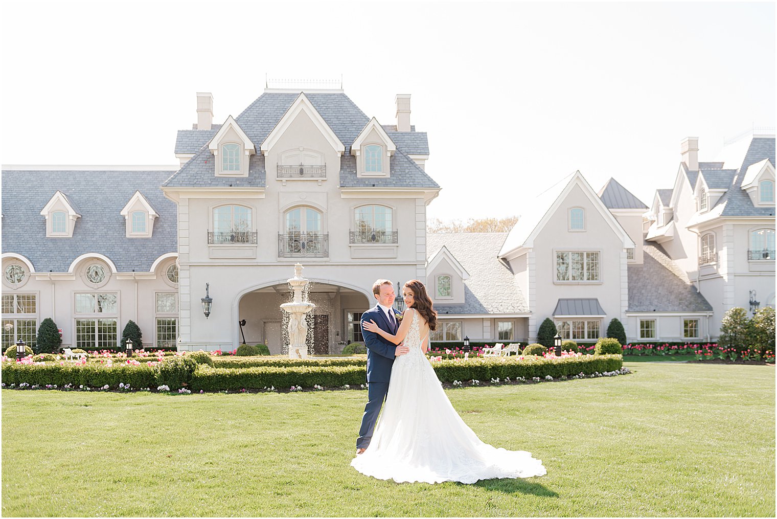 newlyweds kiss on lawn in front of estate house at Park Chateau Estate and Gardens