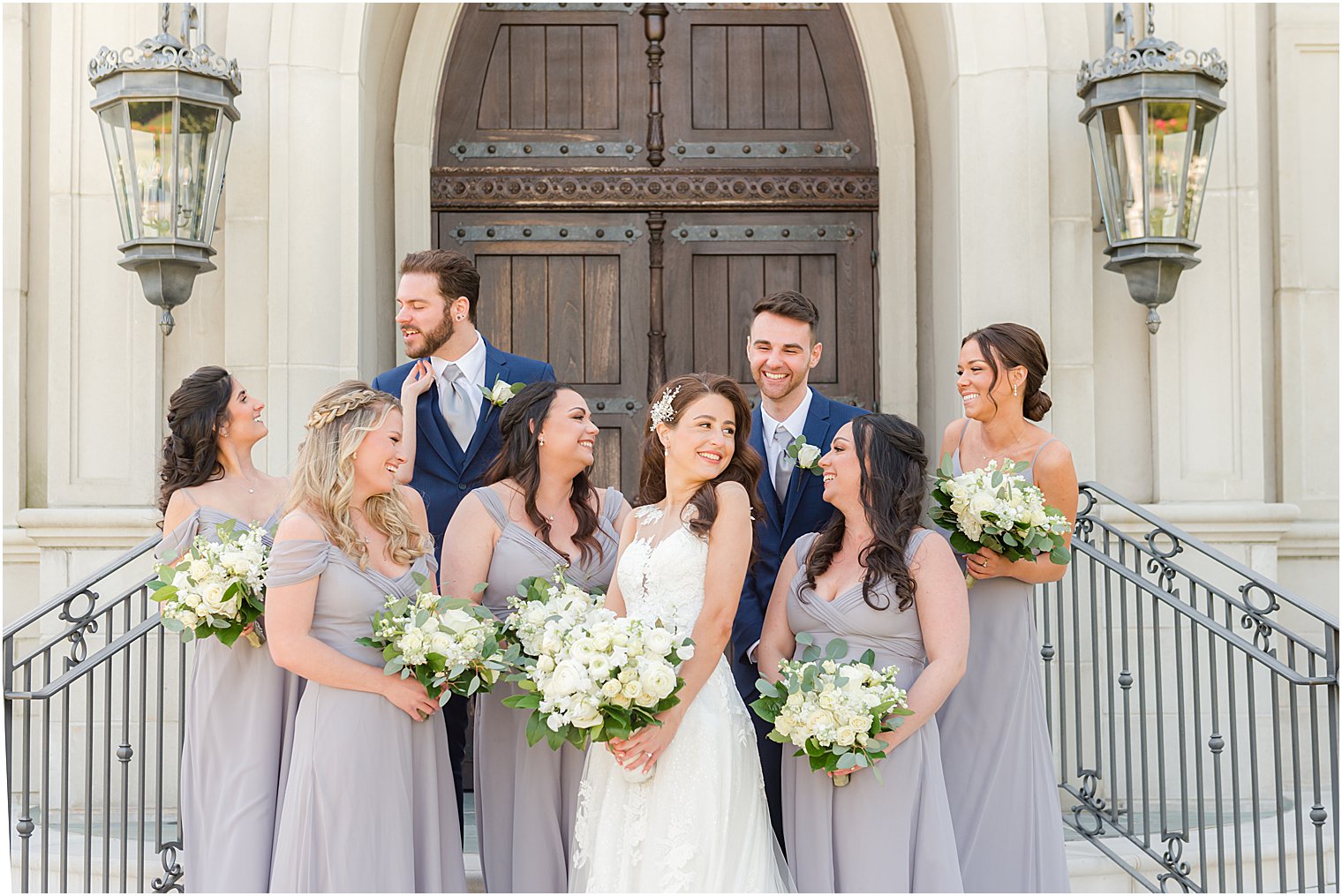 bride smiles with wedding party around her on steps of chapel at Park Chateau Estate and Gardens