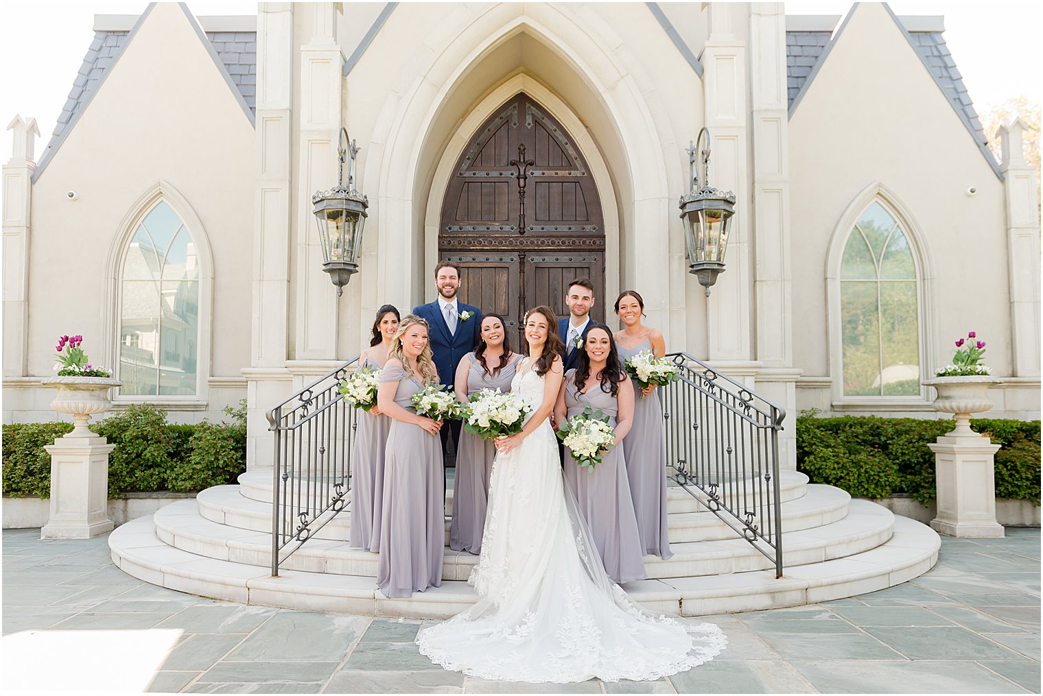 bride poses with wedding party on steps of Park Chateau Estate and Gardens chapel