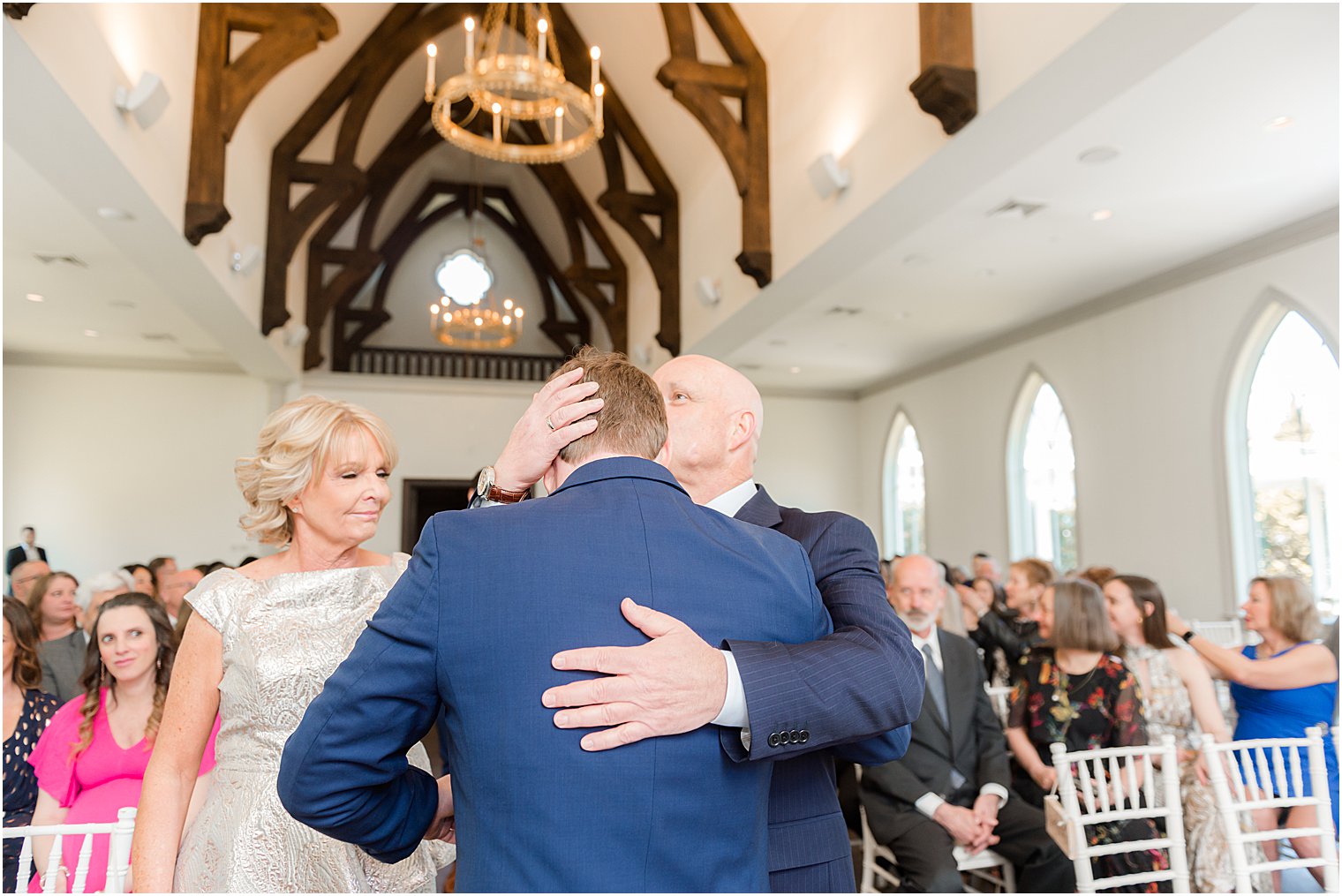 dad kisses groom's head during wedding ceremony in chapel at Park Chateau Estate