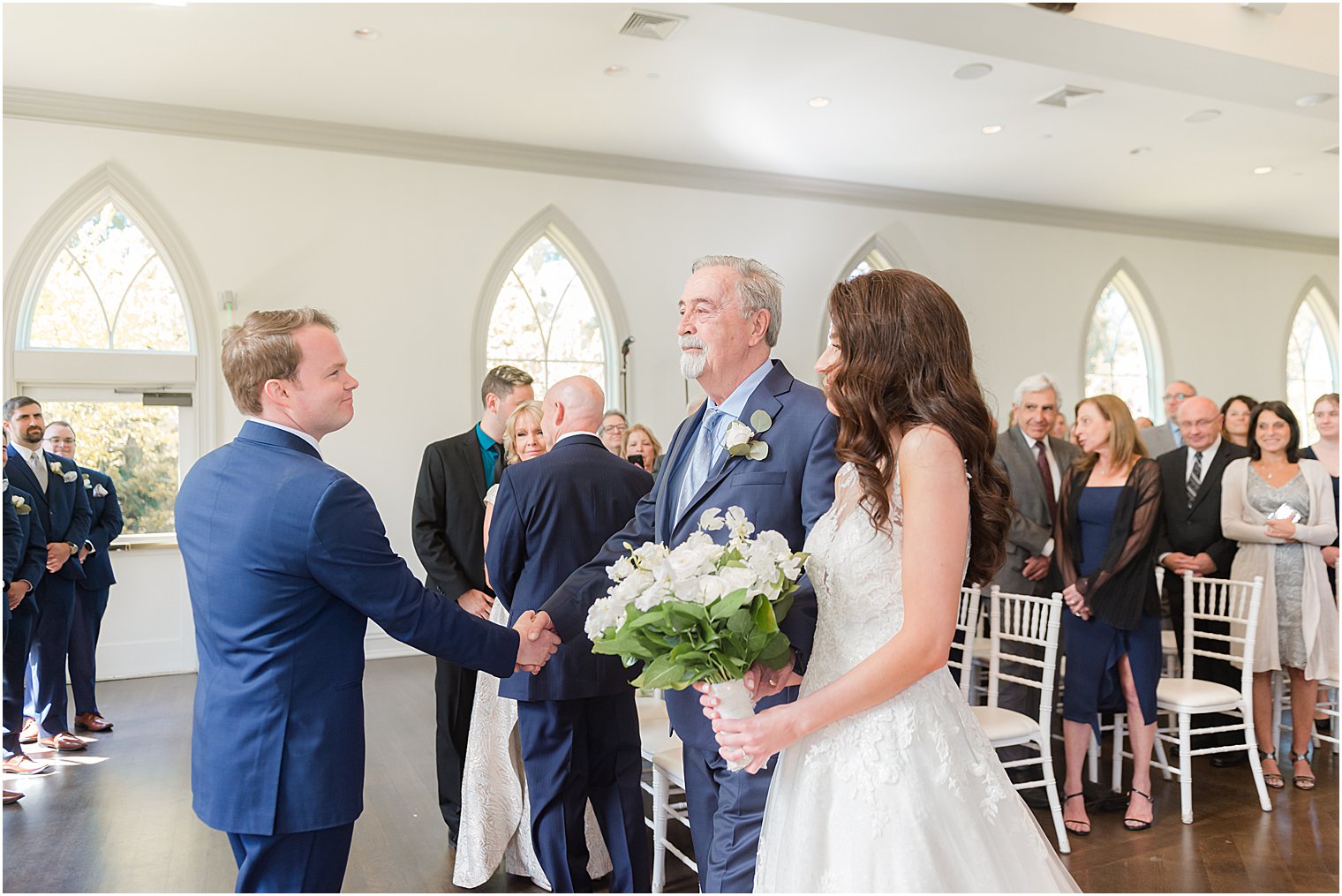 groom shakes hand of father-in-law during wedding ceremony in chapel at Park Chateau Estate