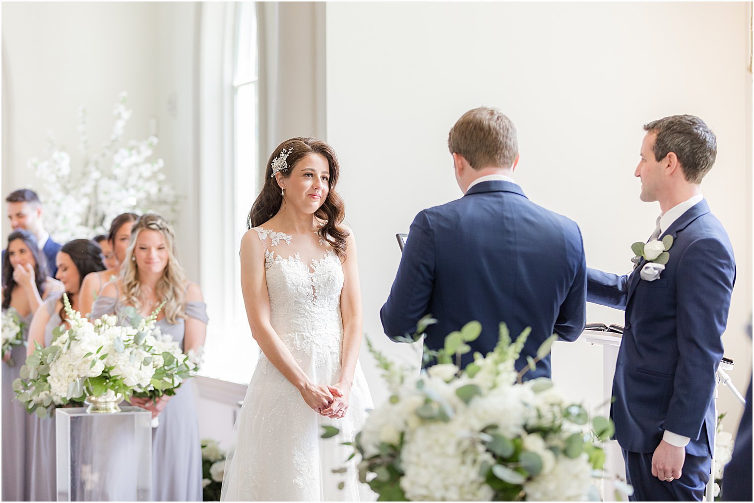bride listens while groom reads vows during wedding ceremony in chapel at Park Chateau Estate
