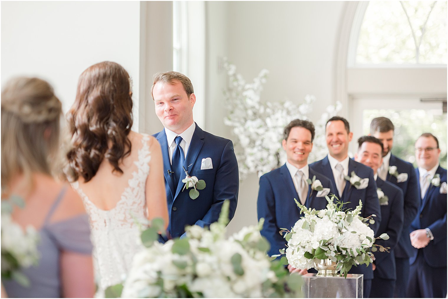 groom smiles at bride during wedding ceremony in chapel at Park Chateau Estate