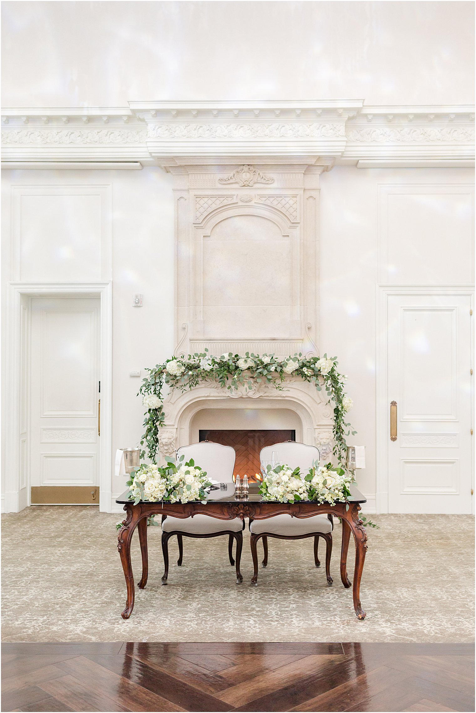 sweetheart table draped with white flowers and greenery by fireplace at Park Chateau Estate