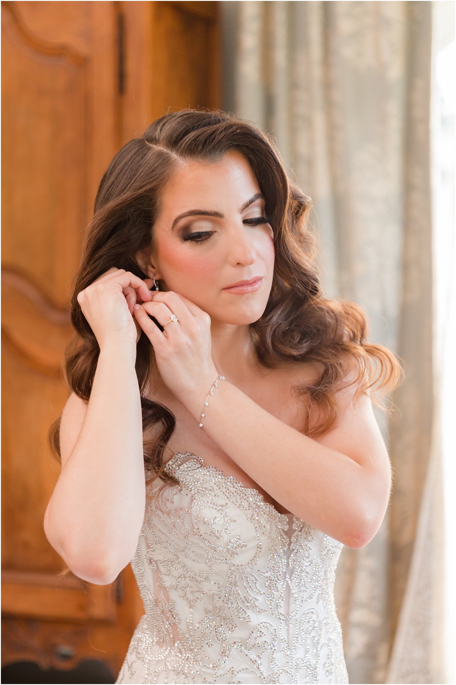 bride adjusts earrings in front of wardrobe at Park Chateau Estate bridal suite 