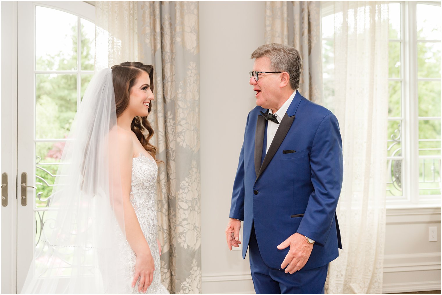 father in navy suit jacket with black lapel is shocked during first look with bride 
