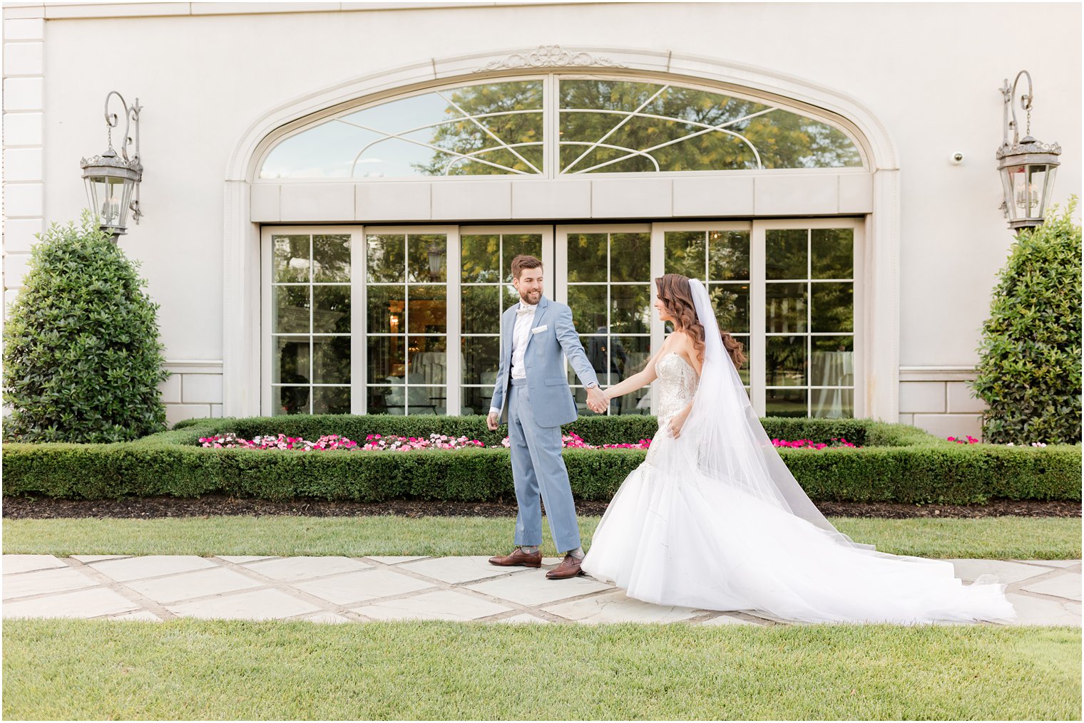 bride and groom hold hands walking by windows of Park Chateau 