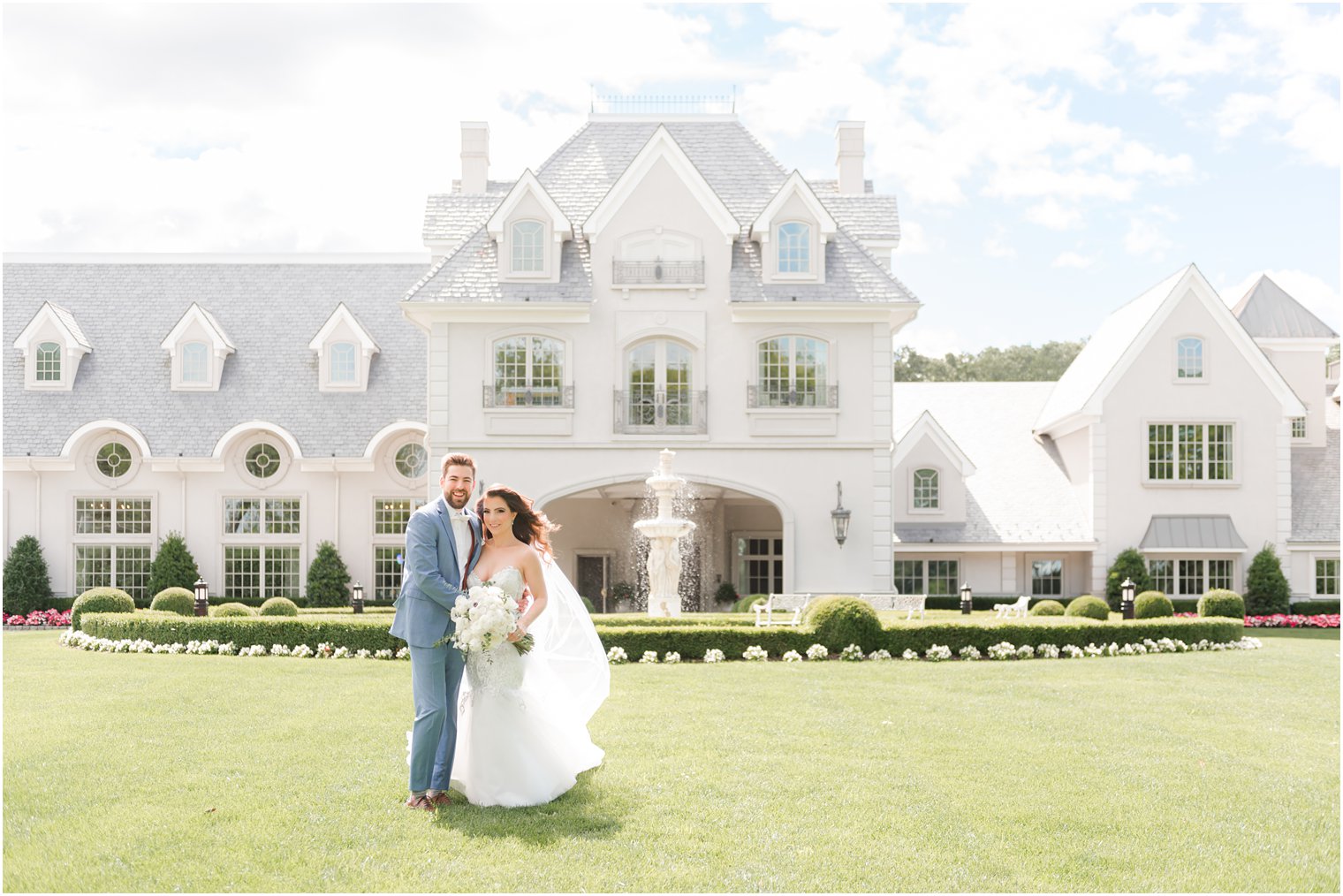 groom hugs bride to him in front of manor house at Park Chateau Estate