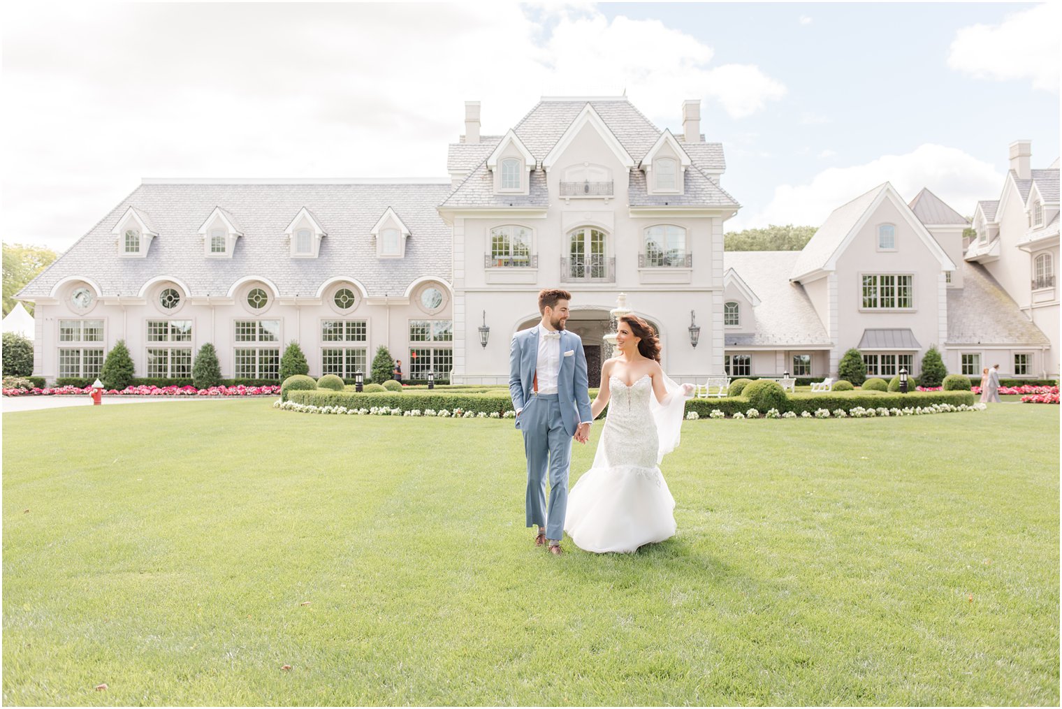 bride and groom hold hands walking on lawn in front of house at Park Chateau Estate 