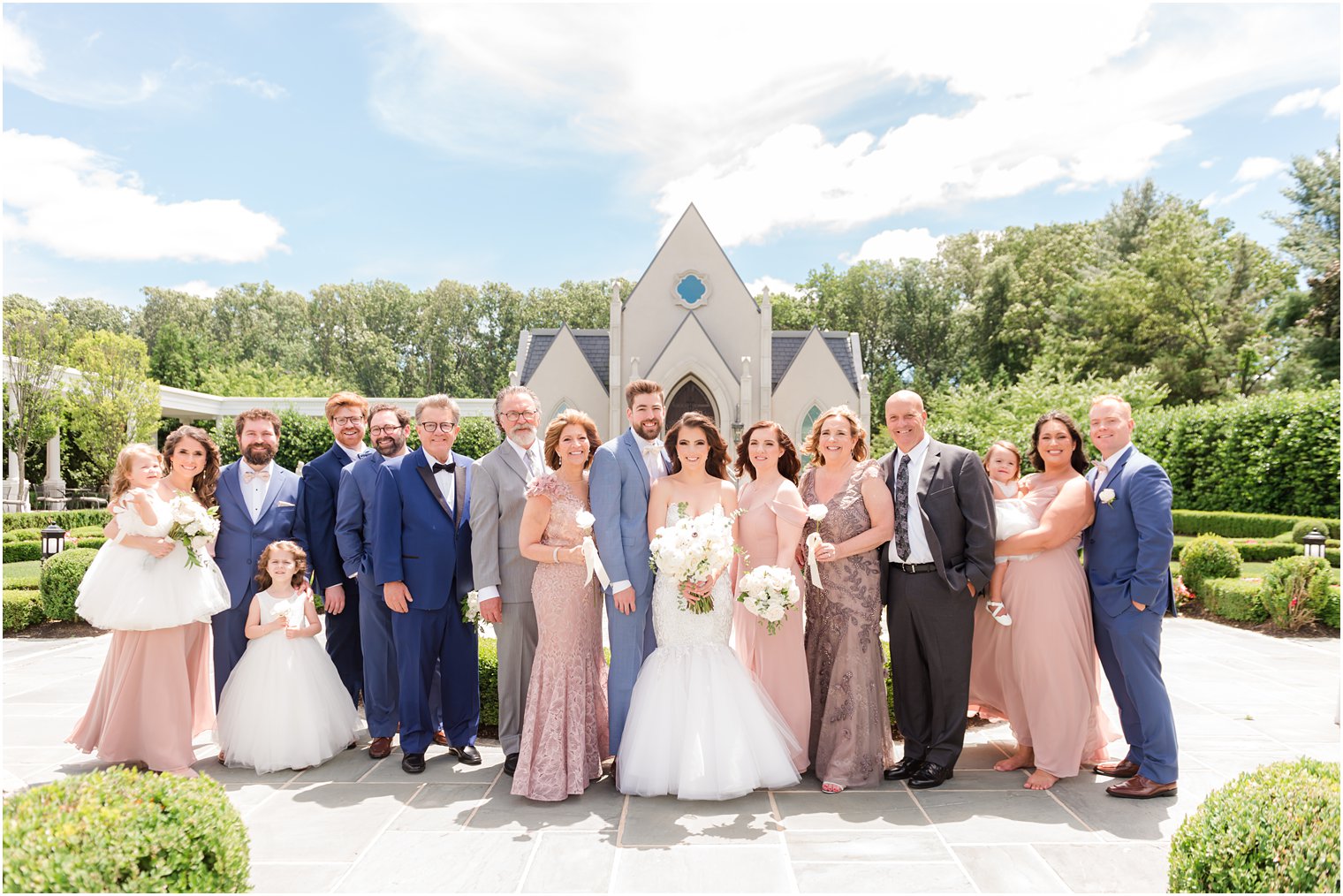 bride and groom pose with families outside Park Chateau Estate chapel in gardens 