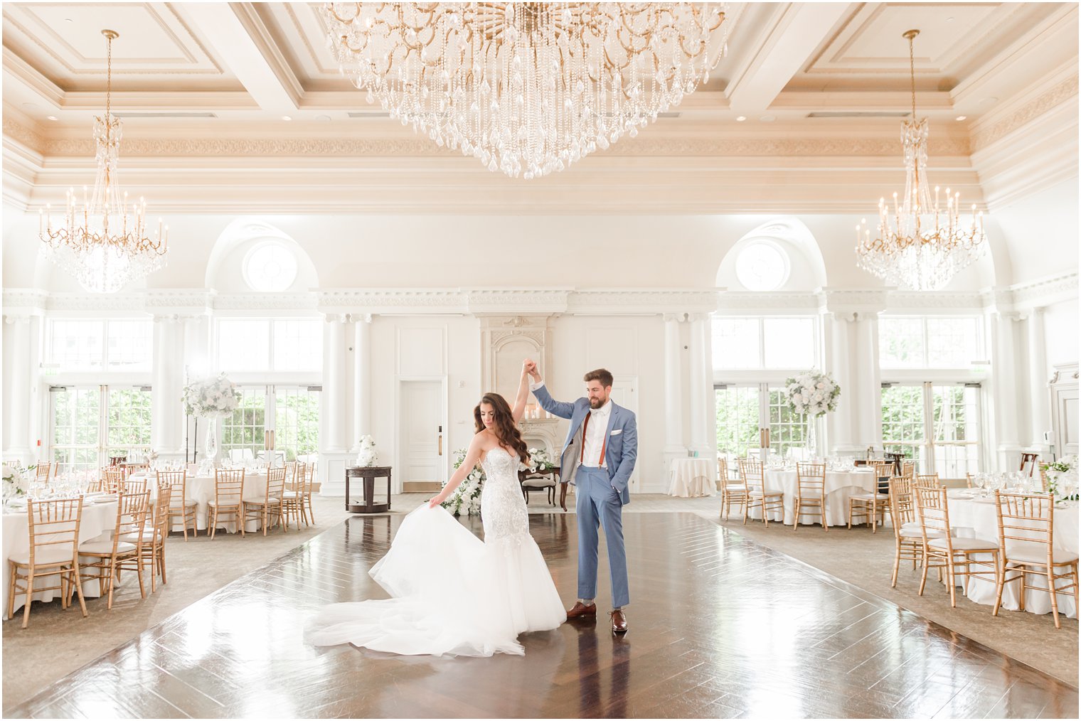 groom twirls bride on ballroom floor inside Park Chateau Estate