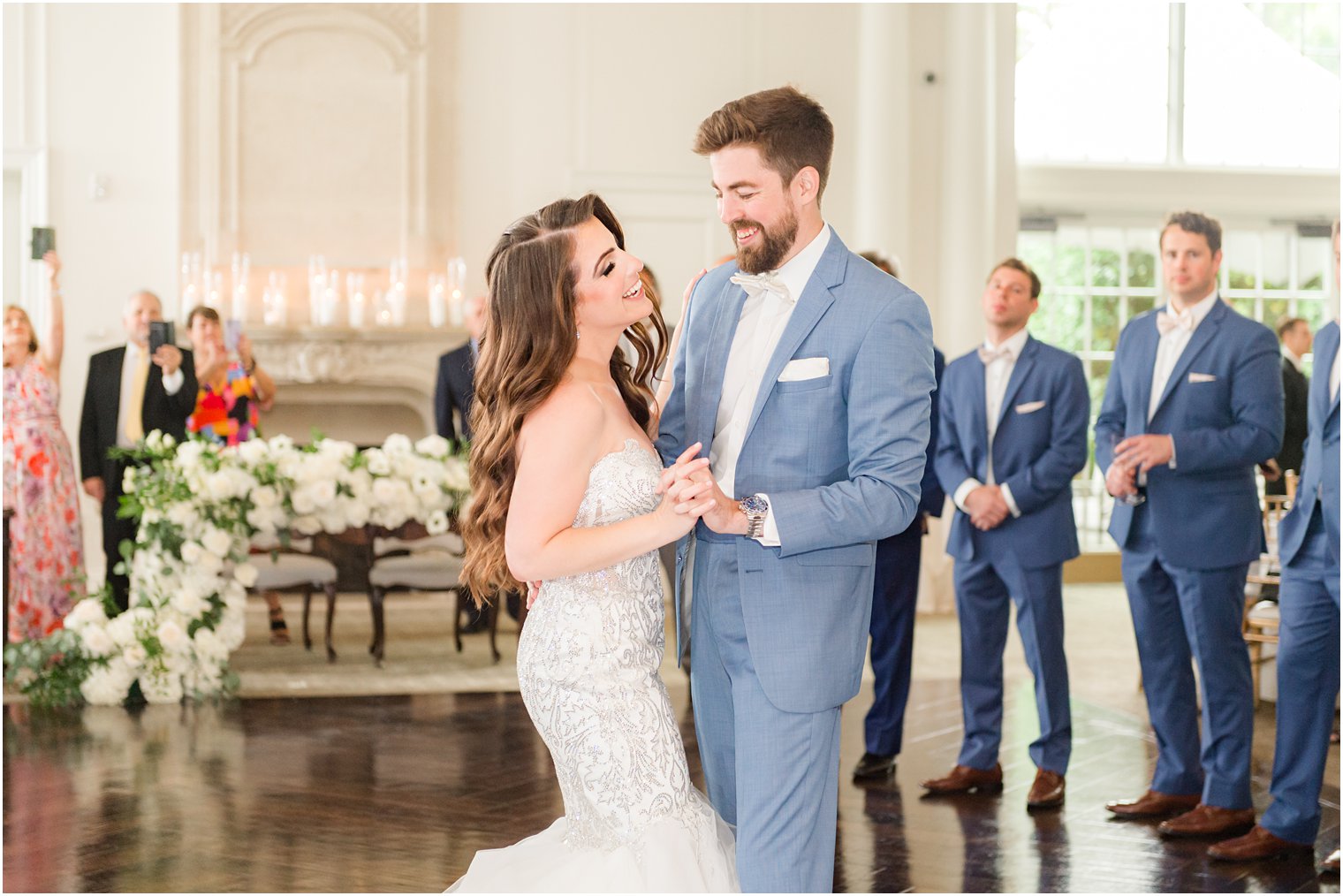 groom in light blue suit smiles at bride while dancing with her at New Jersey wedding reception 