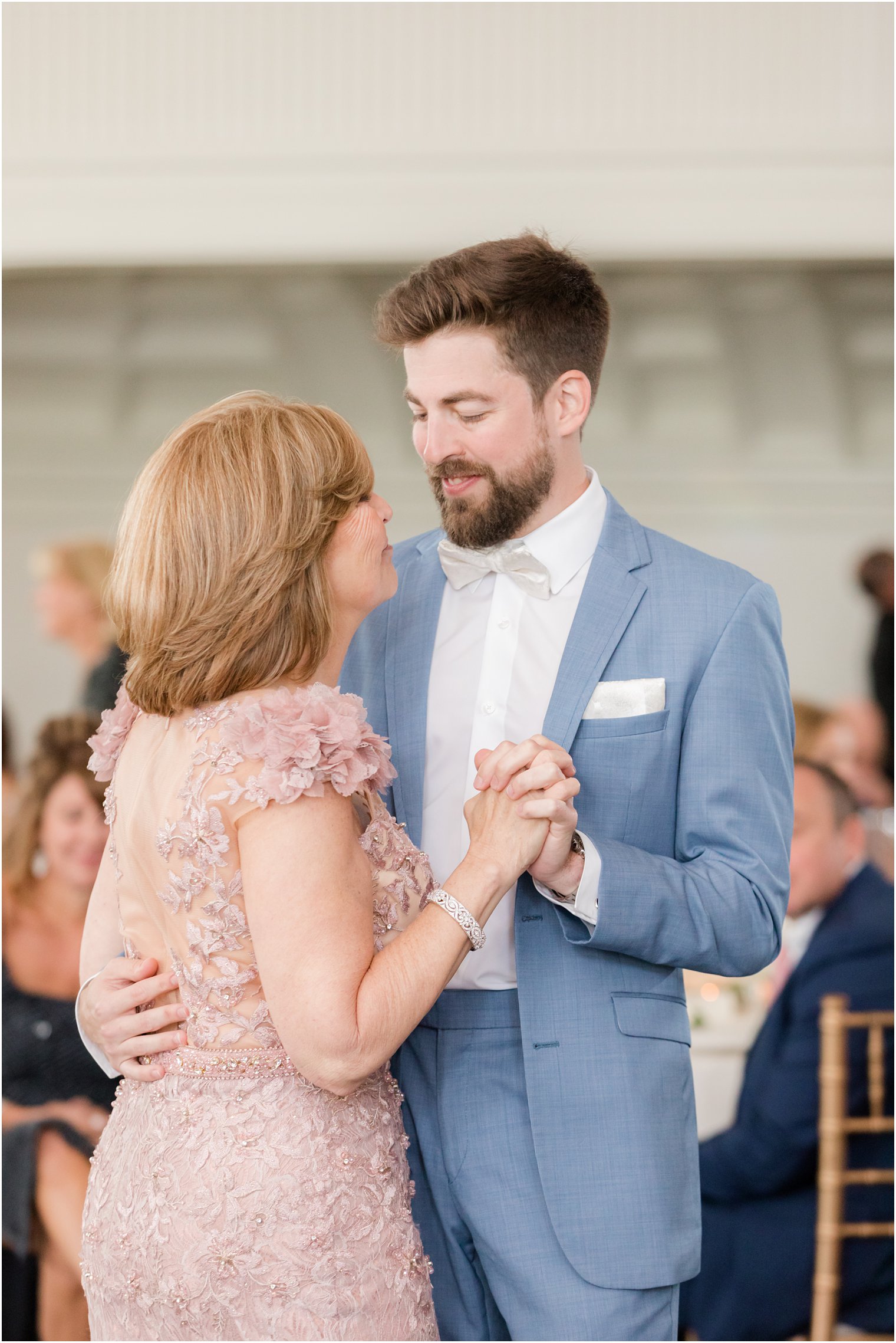 groom in blue suit dances with mom in pink flower inspired gown 