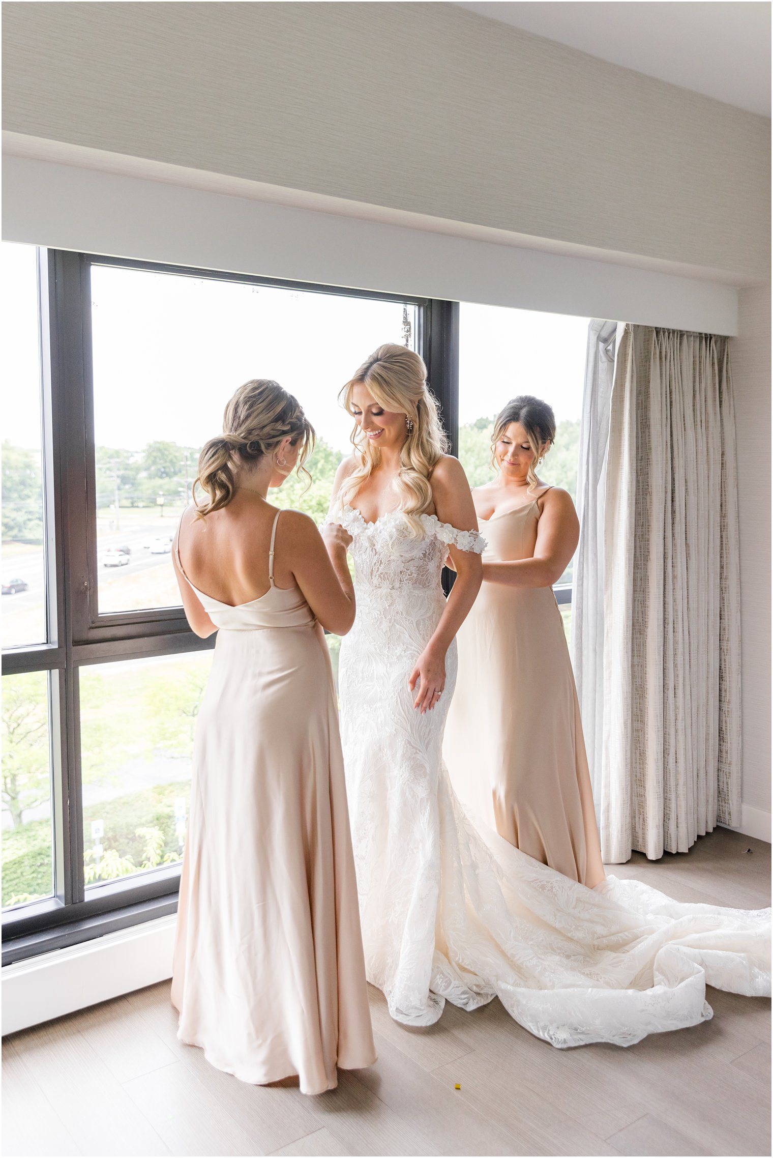 bridesmaids help bride into wedding dress before NJ wedding 
