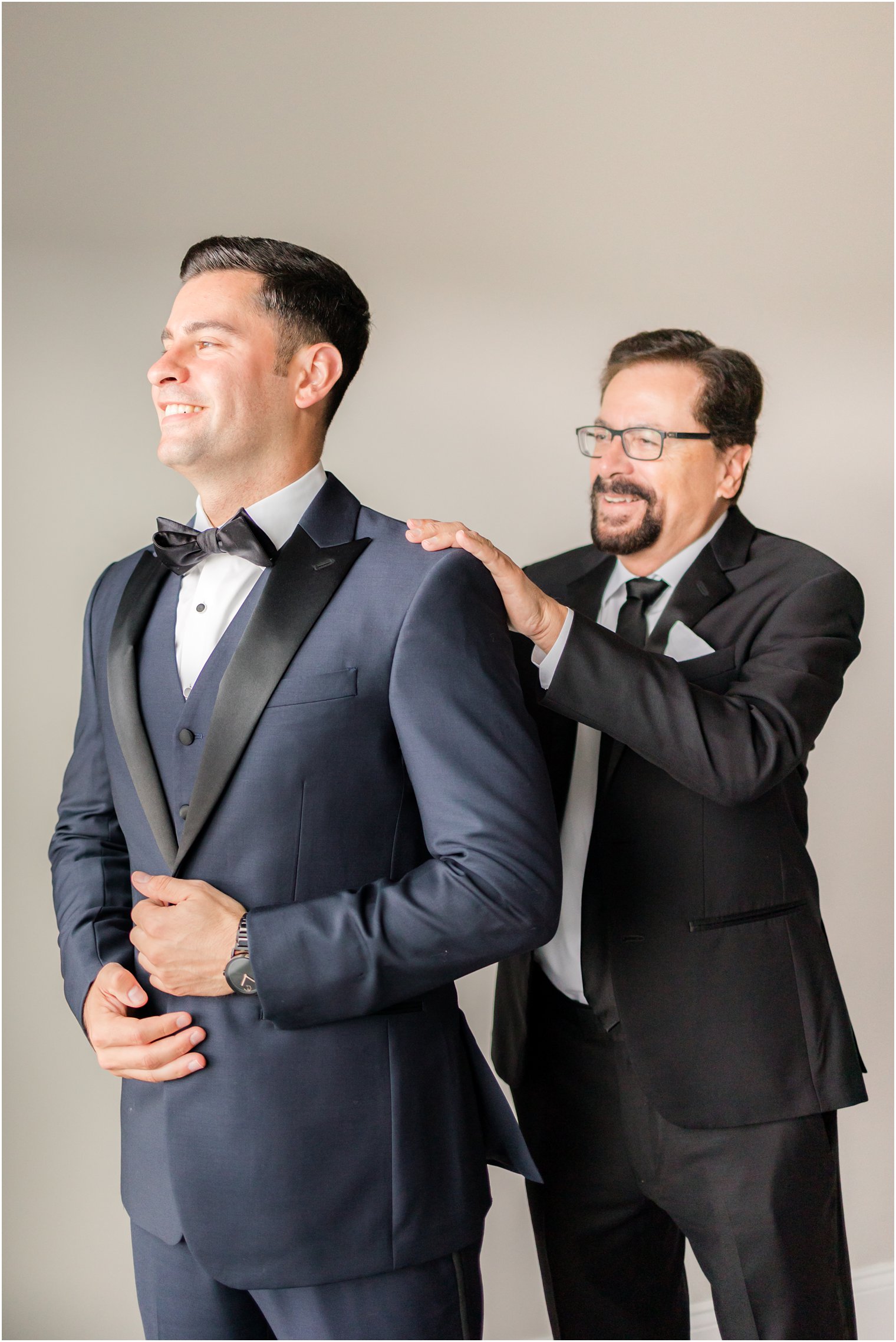 dad helps groom into wedding jacket 