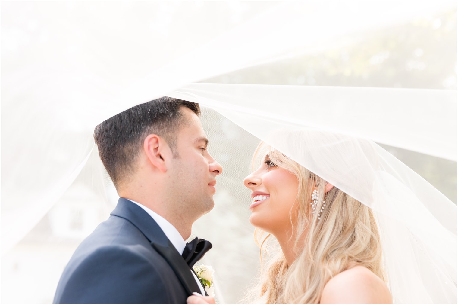 bride and groom smile under veil during garden style wedding at The English Manor