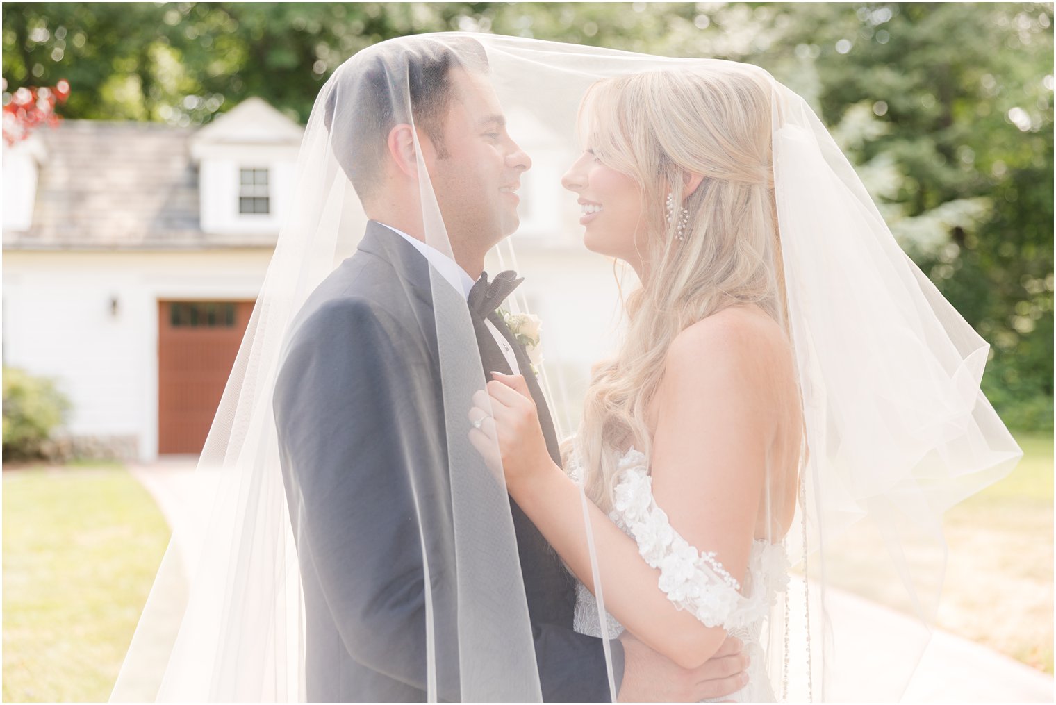 bride and groom smile together under bride's veil during portraits at The English Manor