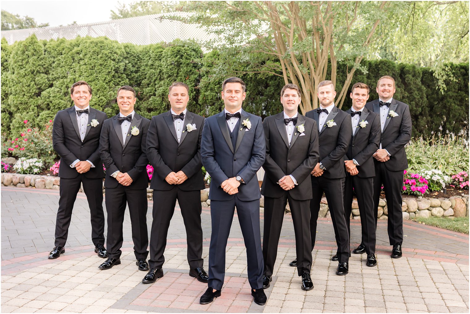 groom in blue suit stands in front of groomsmen in black suits