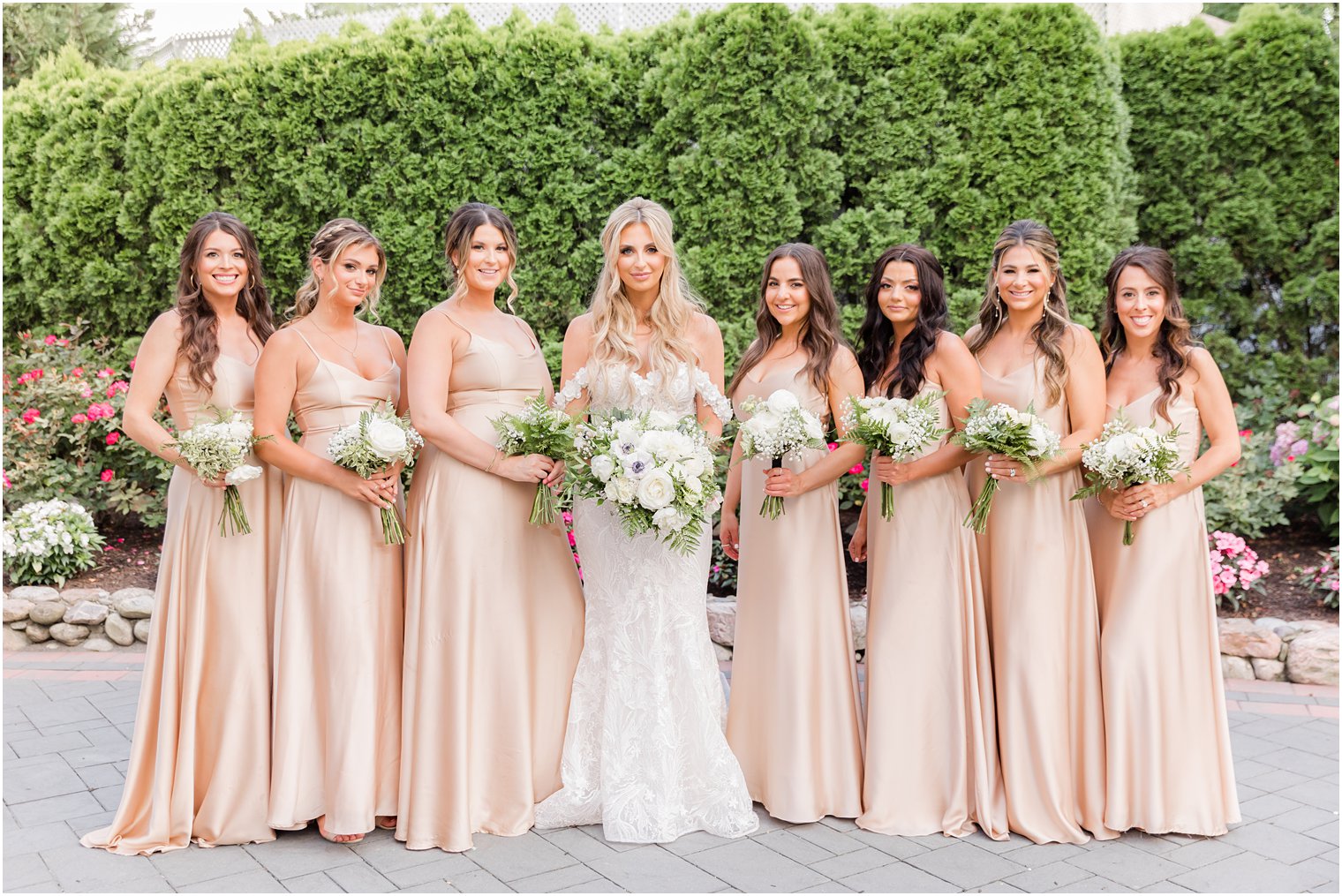 bride stands with bridesmaids in pale pink gowns holding white bouquets at The English Manor
