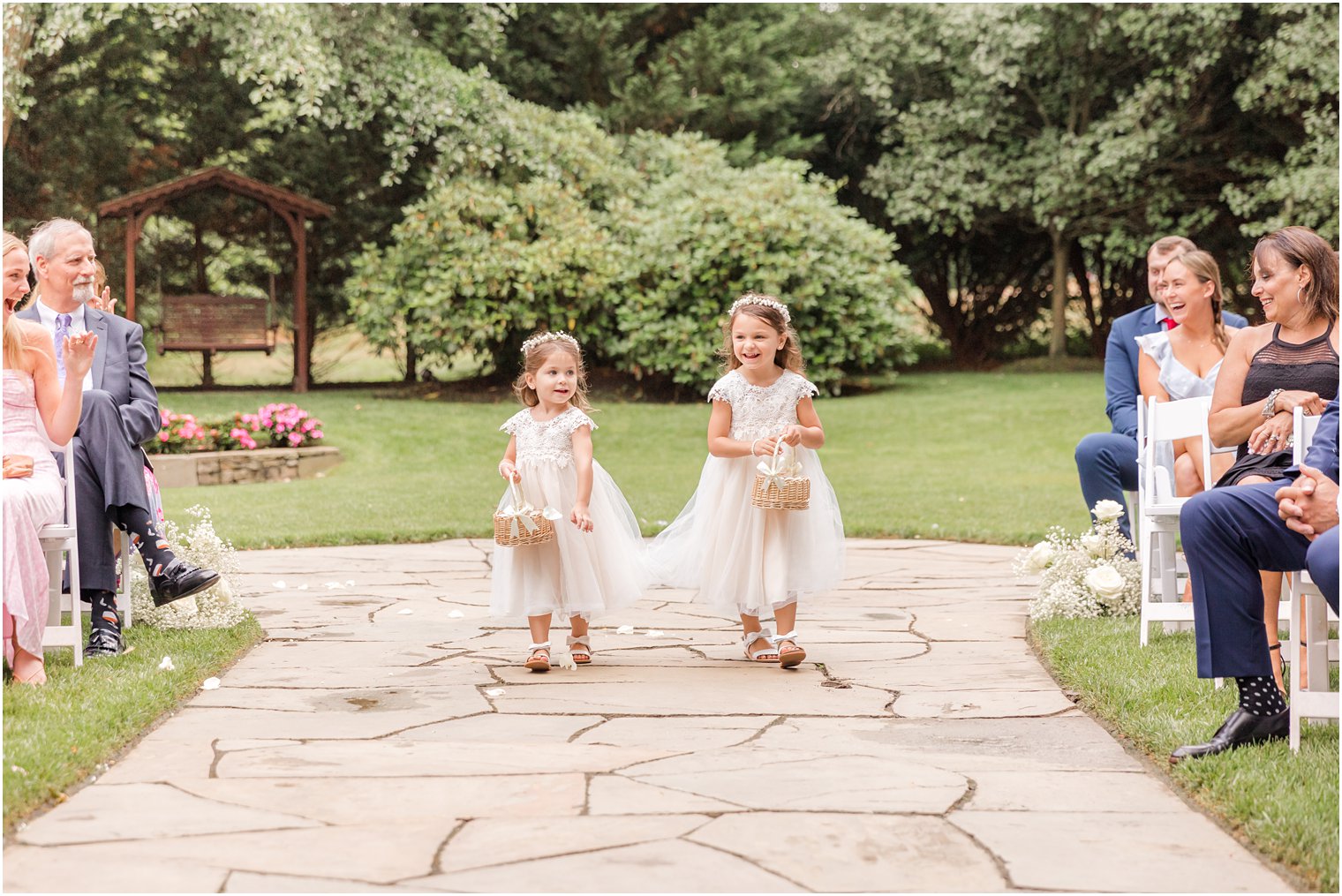 flower girls in white dresses toss rose petals walking down aisle at The English Manor