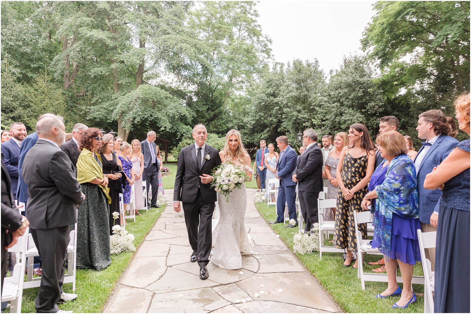 bride walks down aisle with father in garden at The English Manor