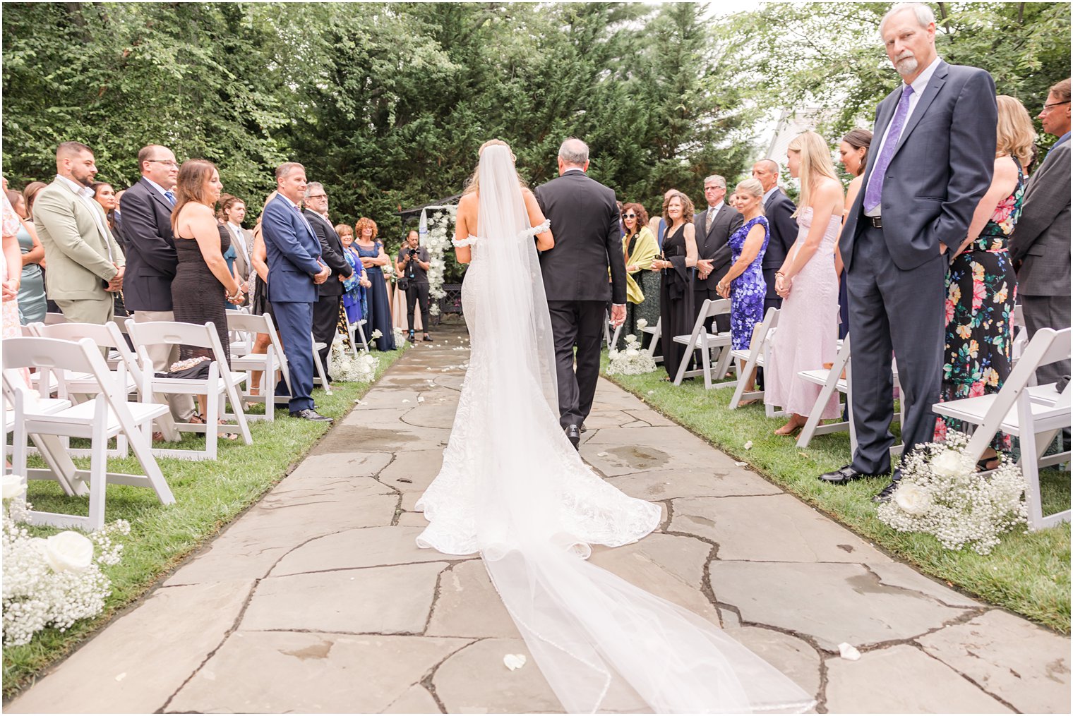 father walks bride down aisle for ceremony in gardens of the English Manor