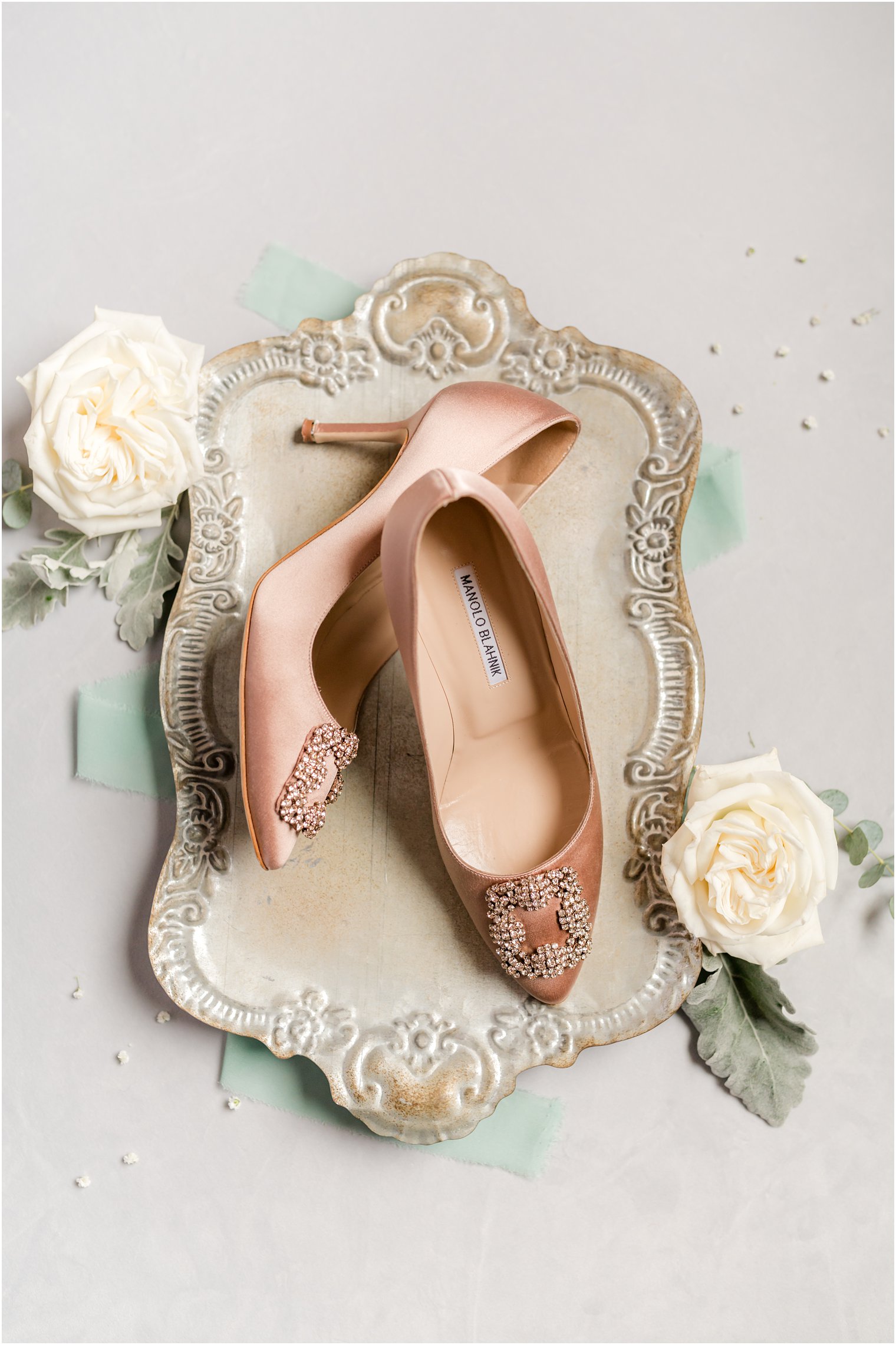 bride's rose gold shoes sit on silver tray with white roses 