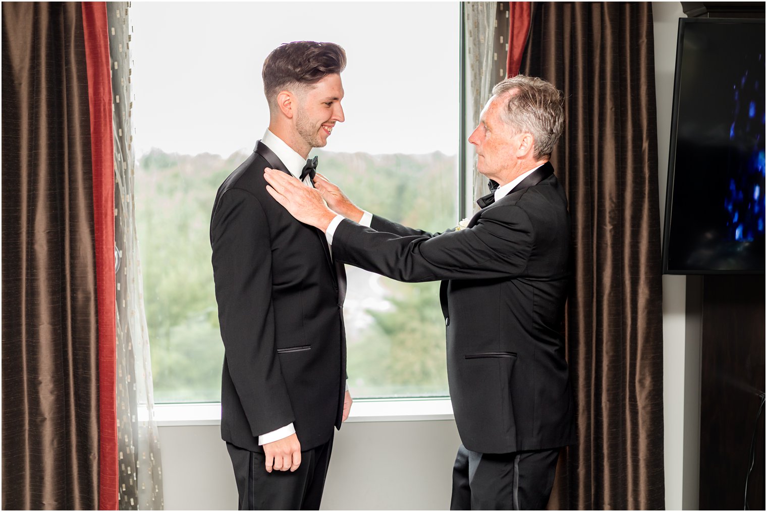 father adjusts jacket and tie for groom before NJ wedding day 