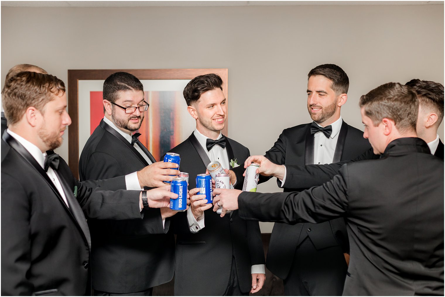 groom toasts beers with groomsmen in black suits 