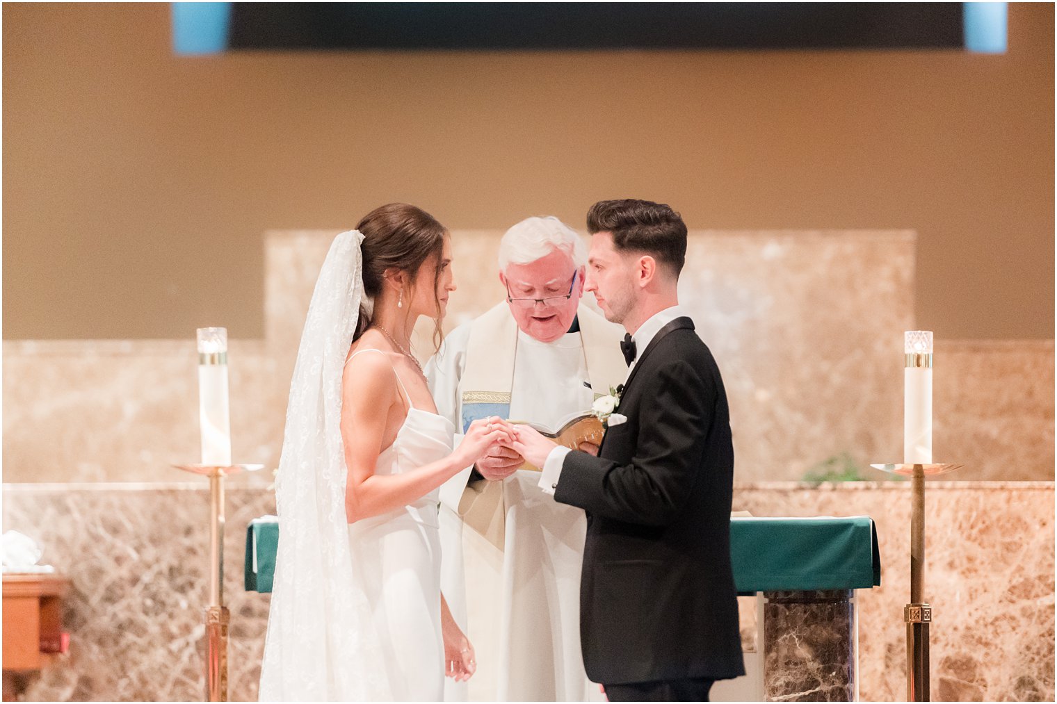 newlyweds look at each other exchanging rings during traditional church ceremony in small New Jersey church