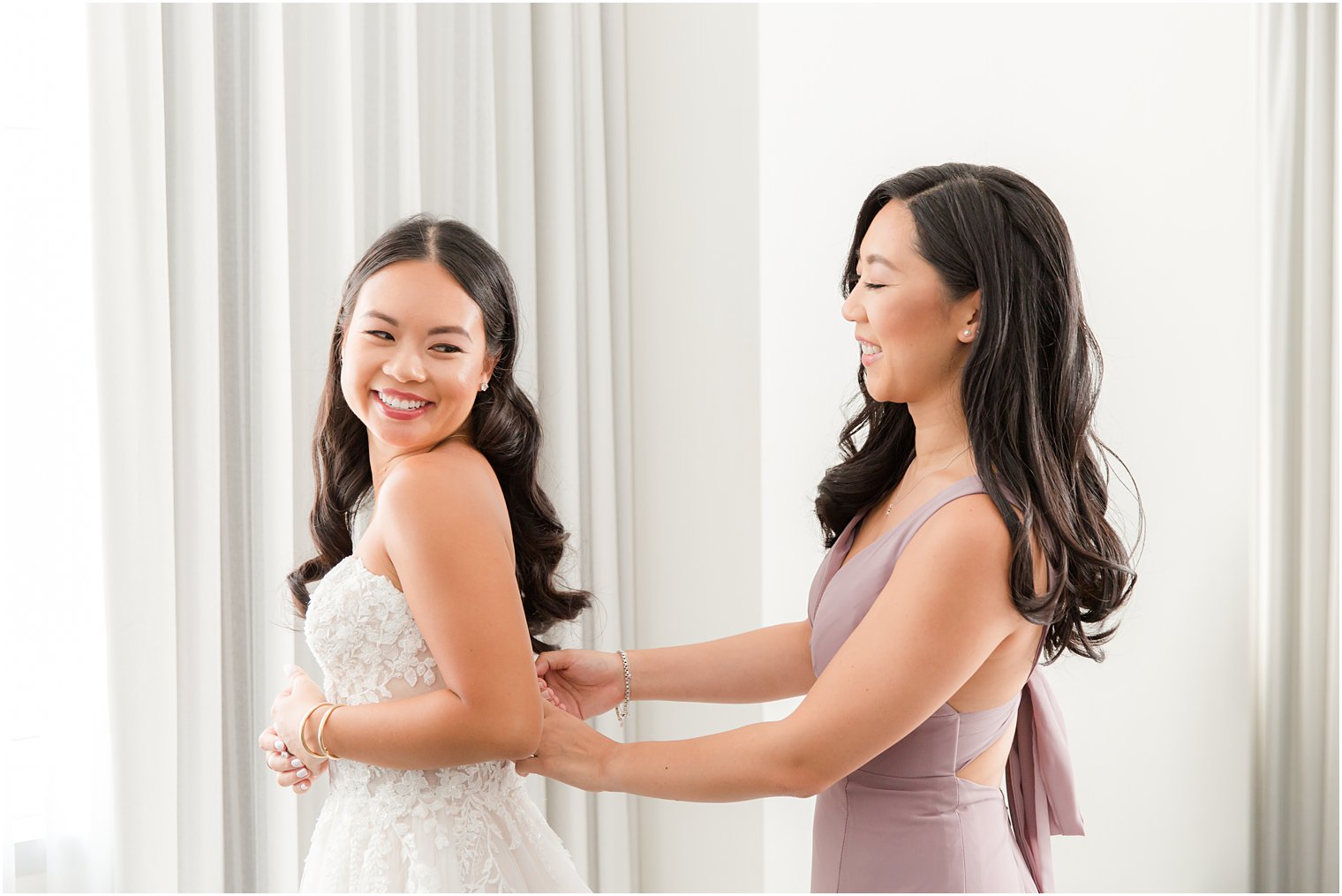 bridesmaid helps bride into wedding dress before Philly wedding 