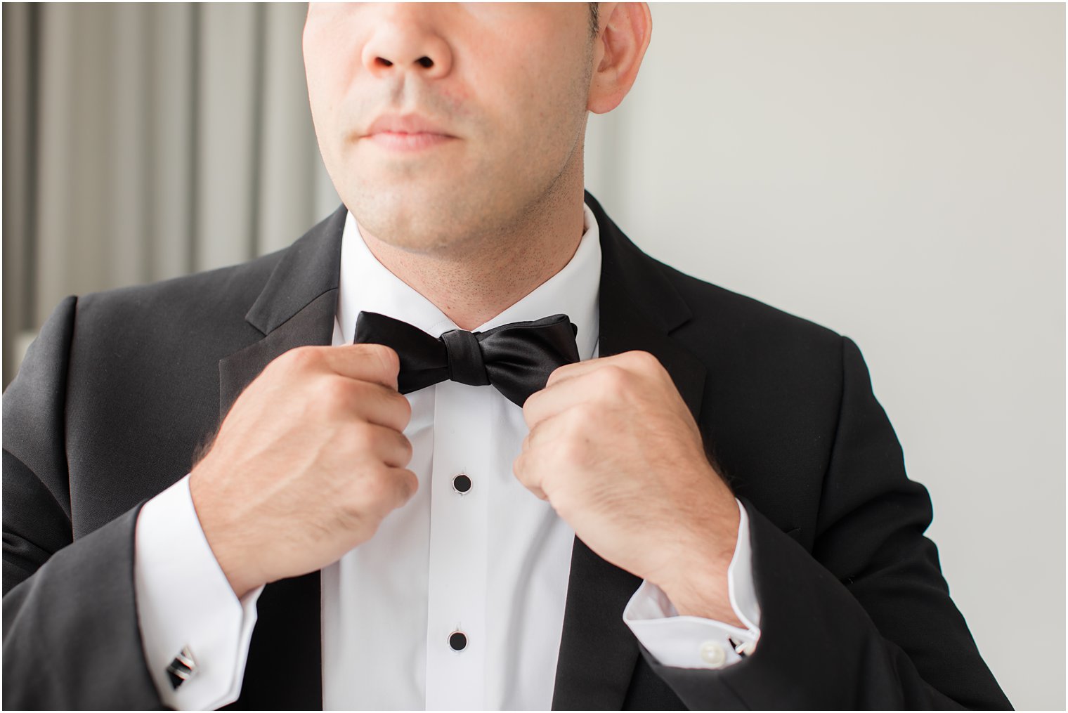 groom adjusts bowtie for tux at the Ballroom at the Ben