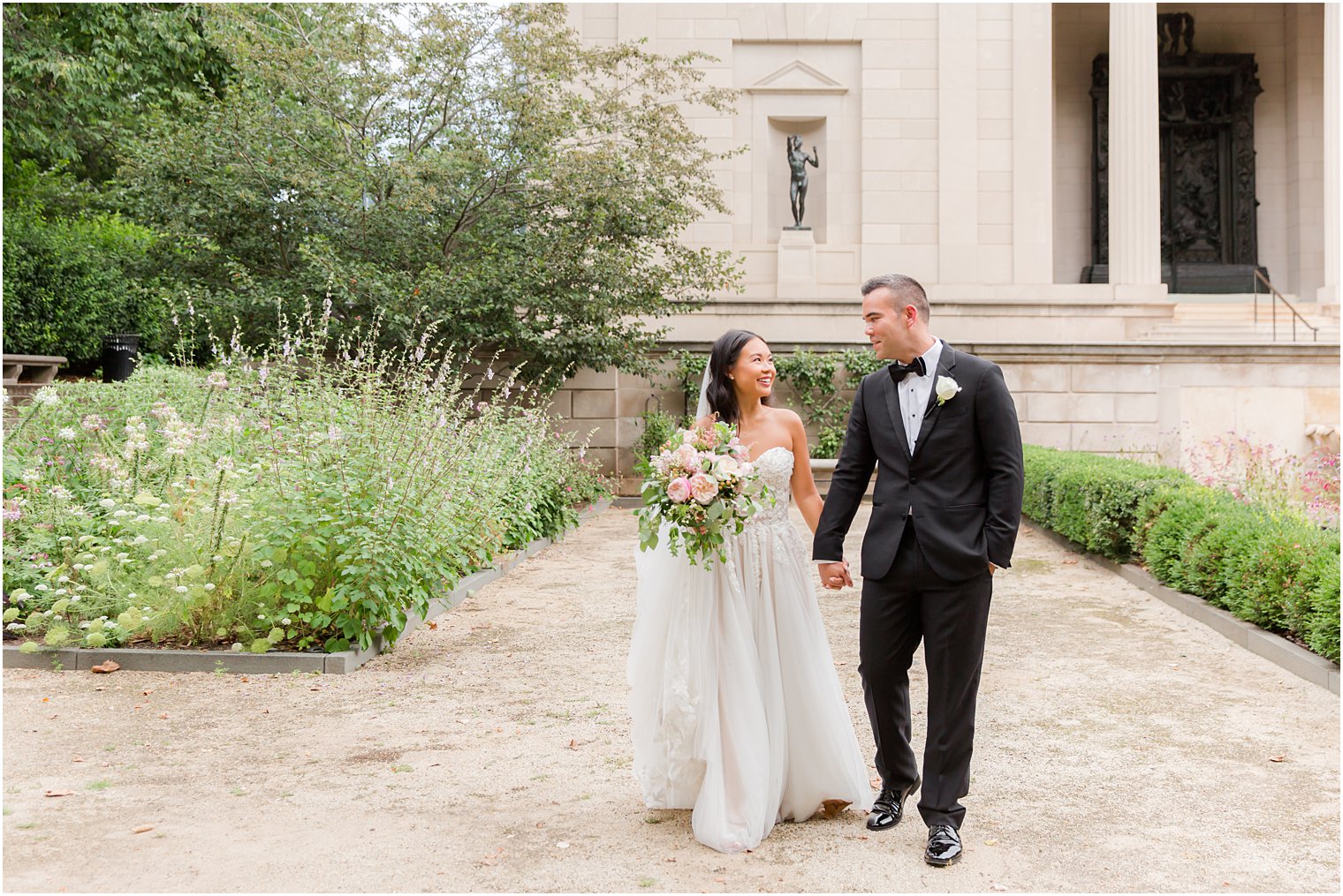 bride and groom hold hands walking through gardens at the Rodin Museum