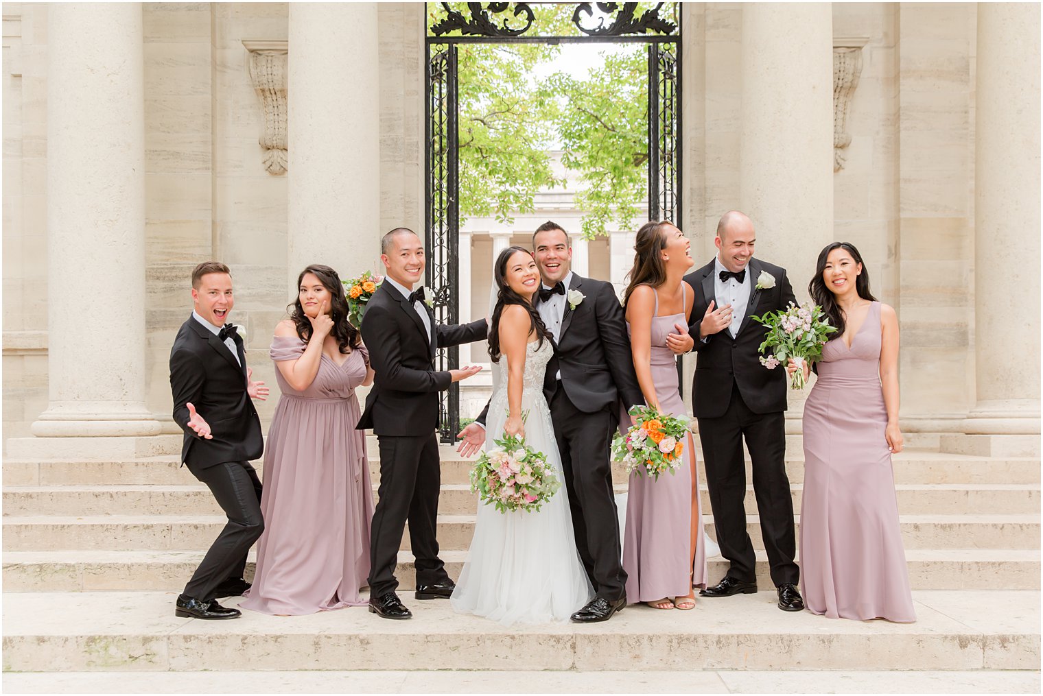 bride and groom pose with wedding party in black tuxes and mauve gowns at the Rodin Museum