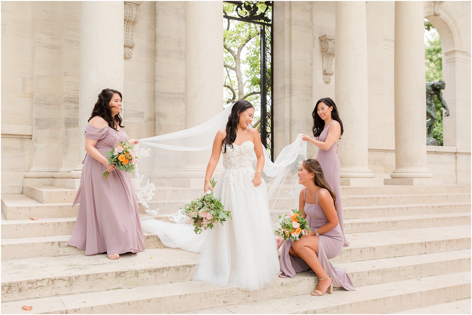 bridesmaids help bride with wedding gown on steps at the Rodin Museum