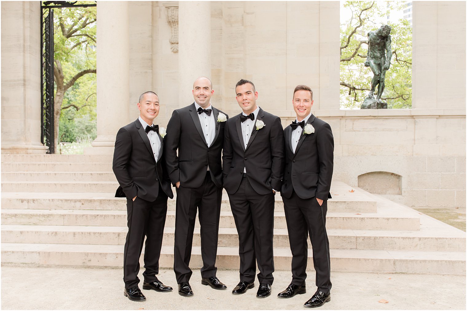 groom in black tux stands with three groomsmen on steps at the Rodin Museum