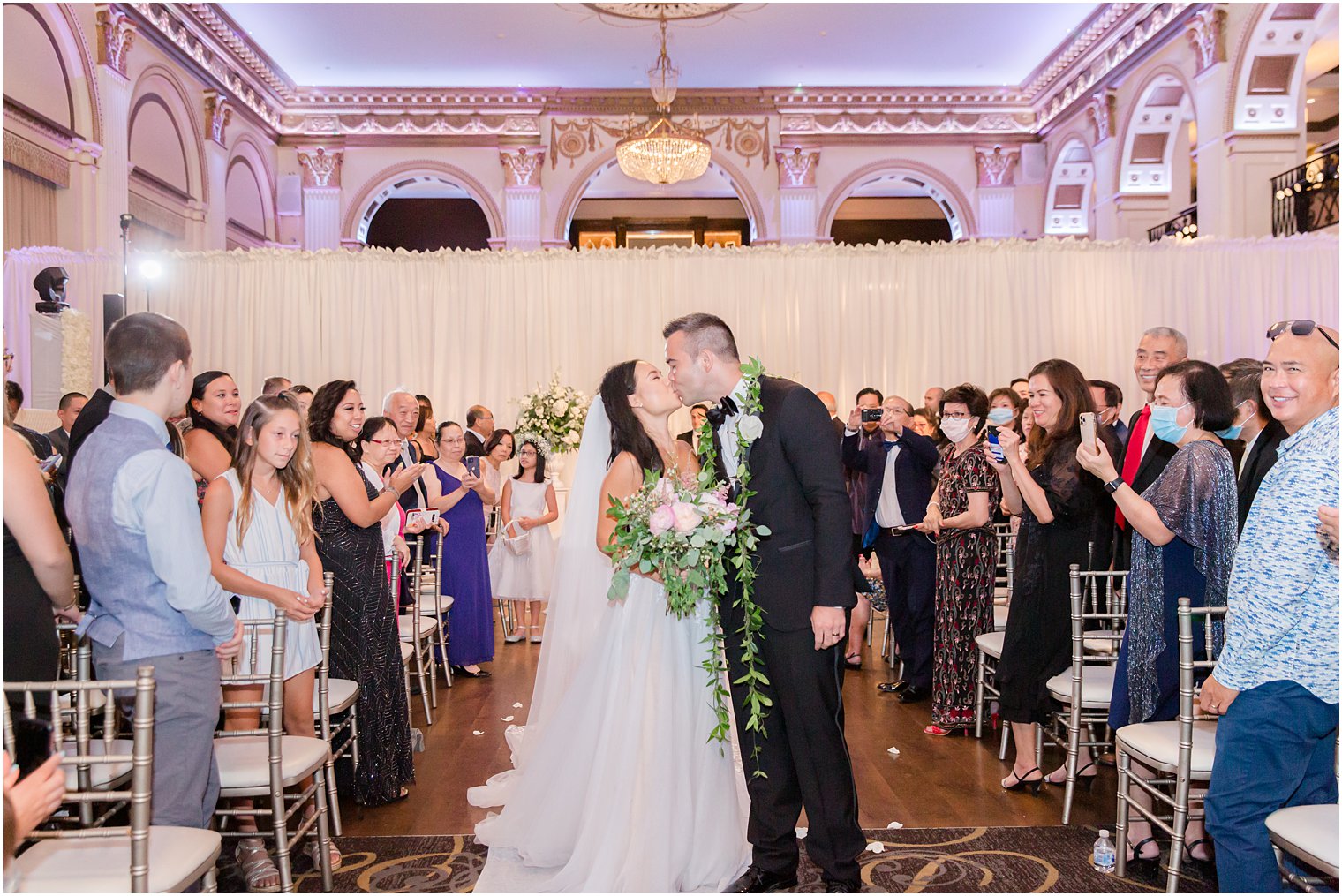 bride and groom kiss between guests after ceremony at the Ballroom at the Ben