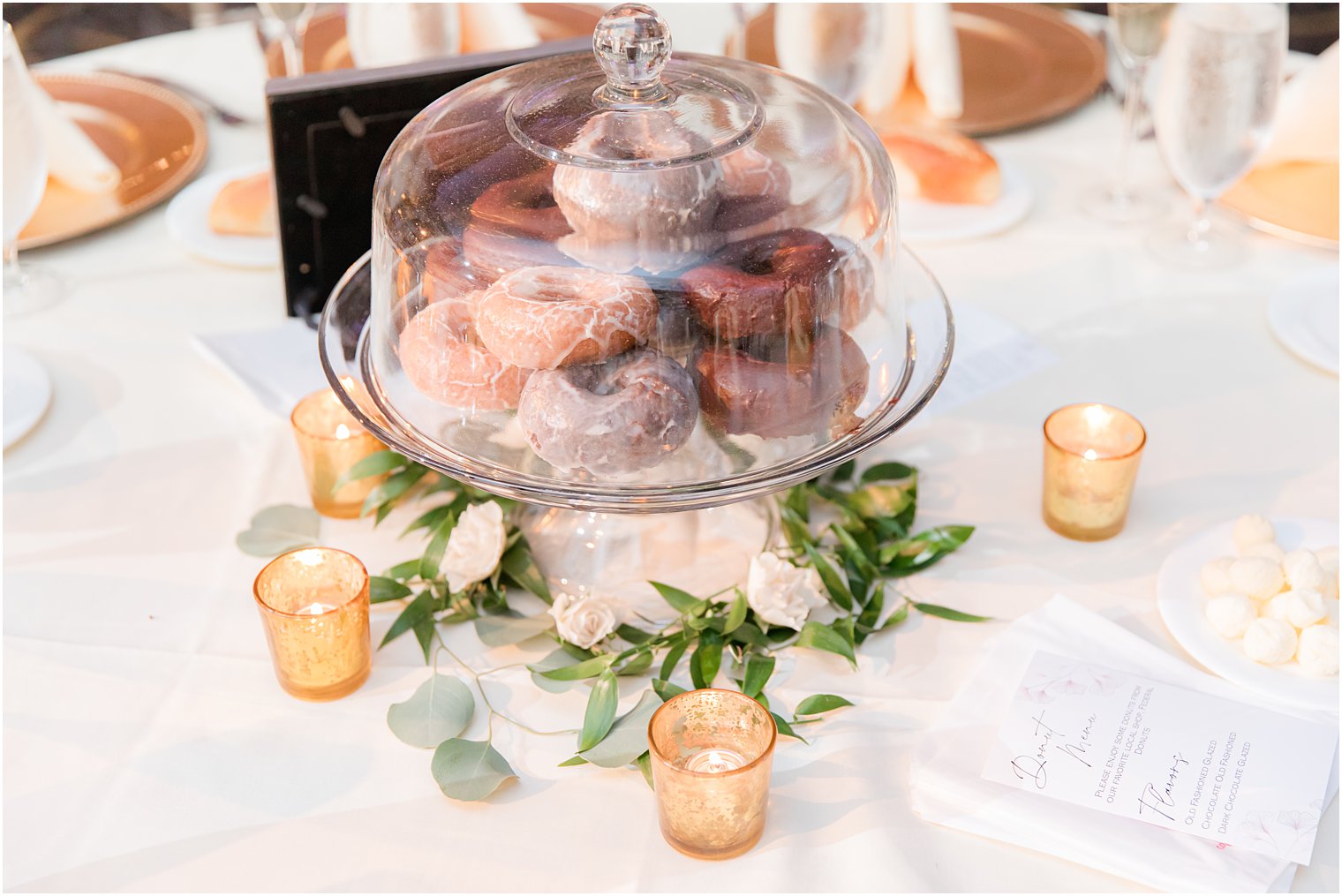 donuts sit on cake stand in center of table at reception at the Ballroom at the Ben