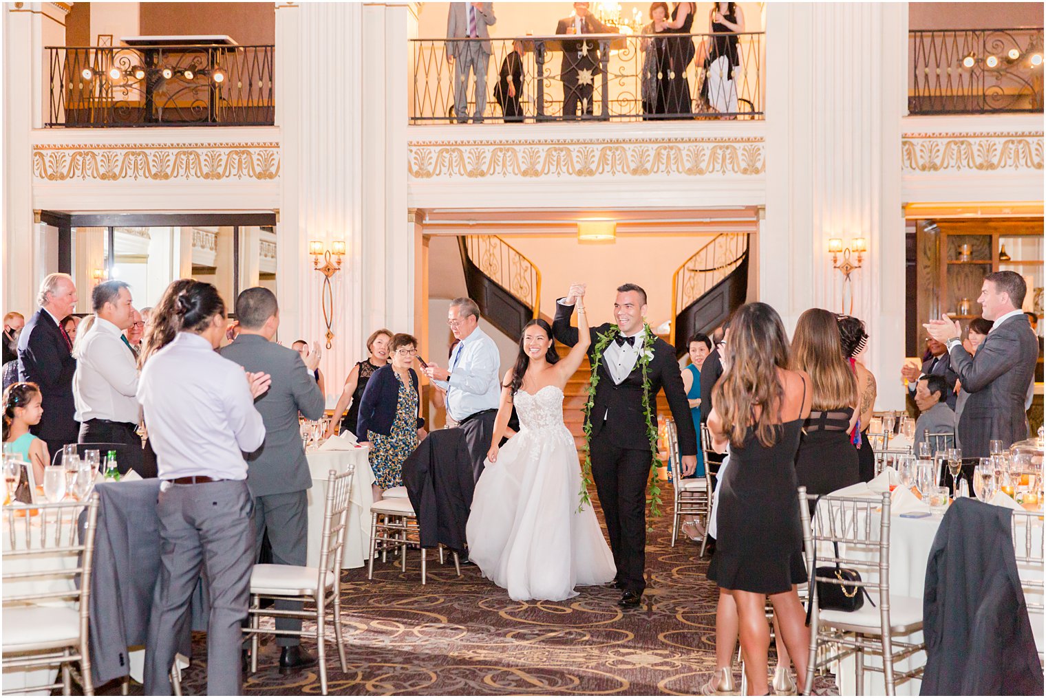 bride and groom walk into wedding reception waving to guests 