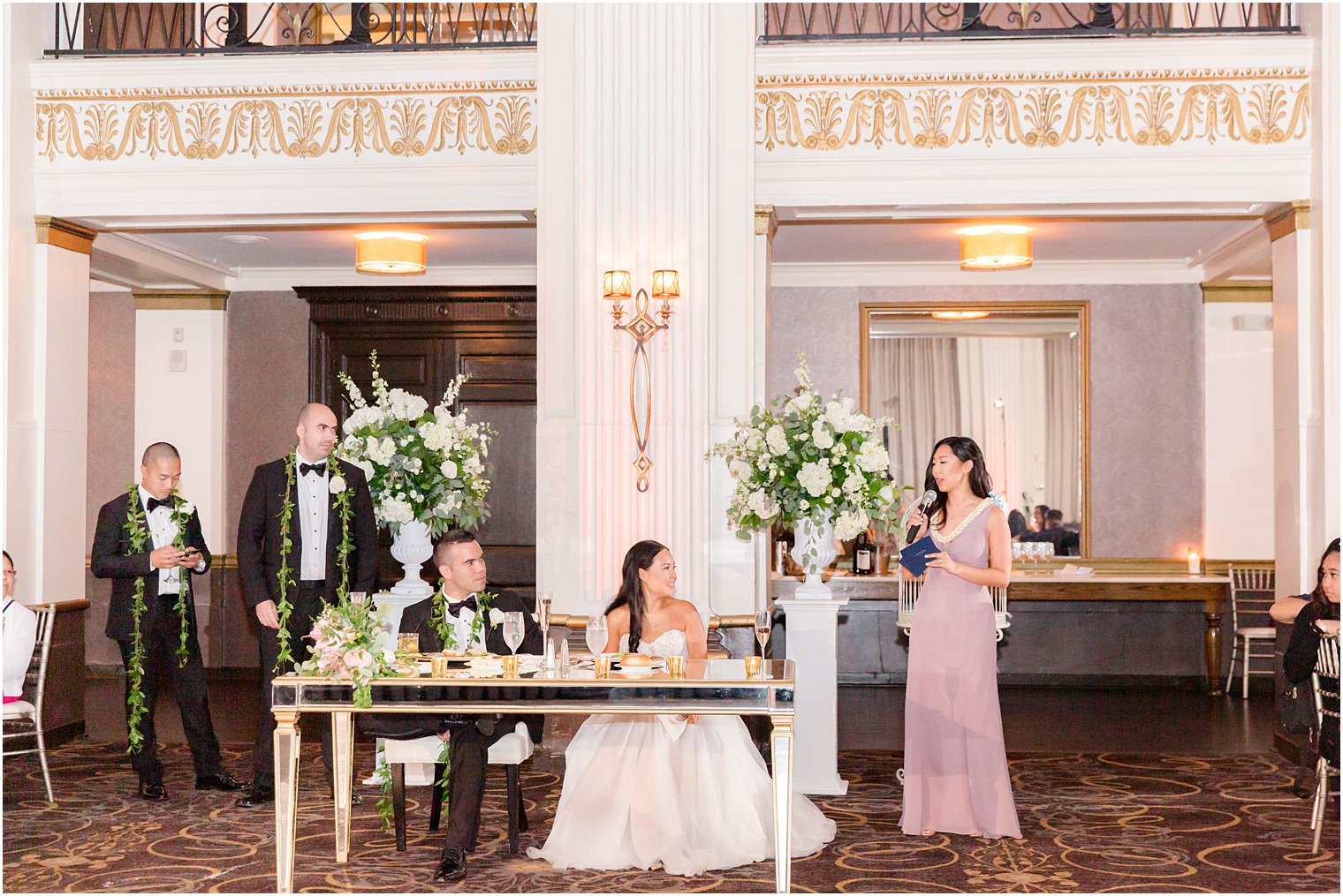 bridesmaid reads speech to bride and groom during reception 