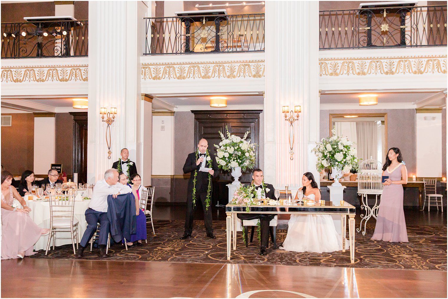 groomsman reads speech to bride and groom during wedding reception 