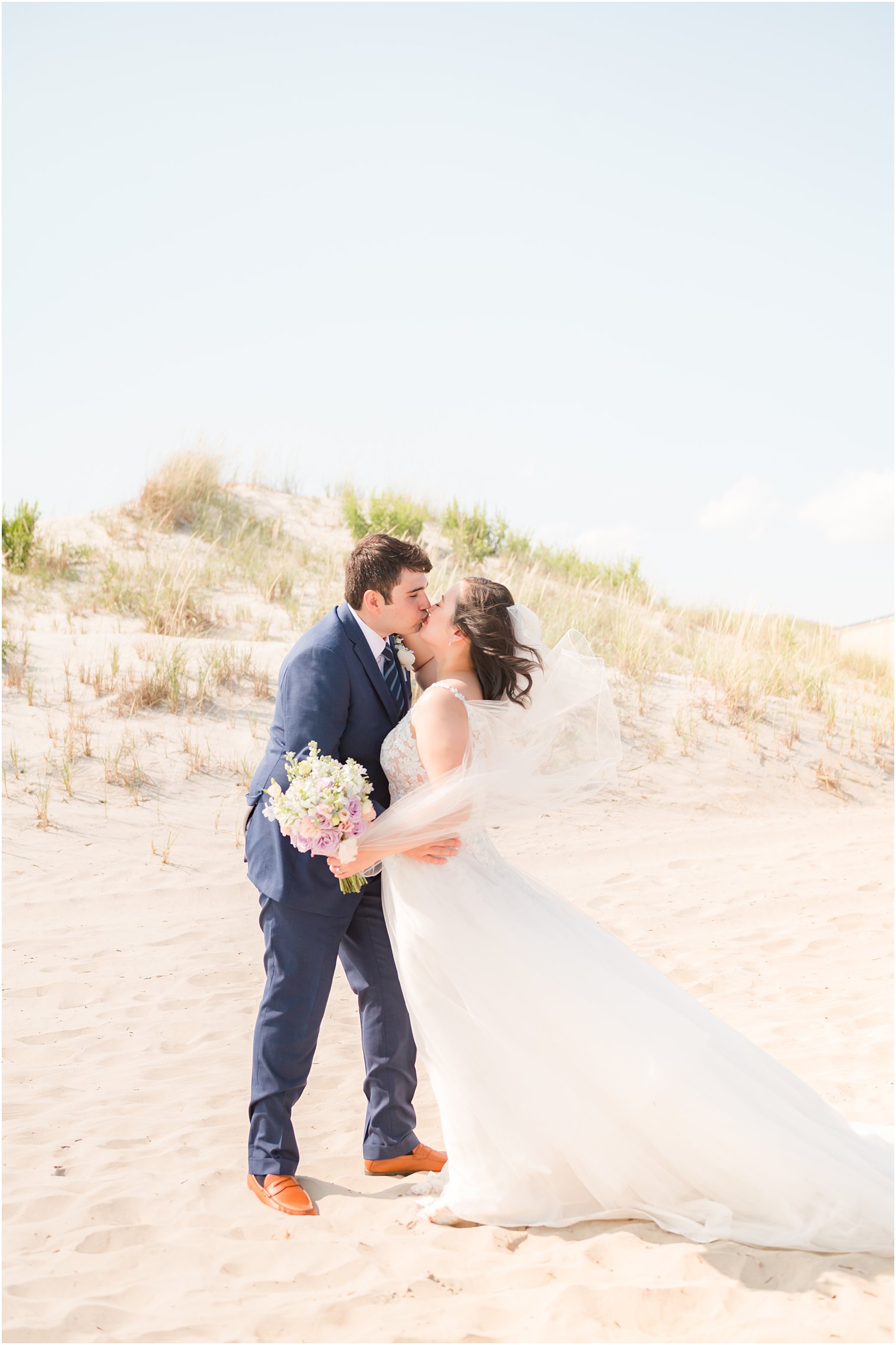 bride and groom kiss on sand dune at Avalon Beach NJ