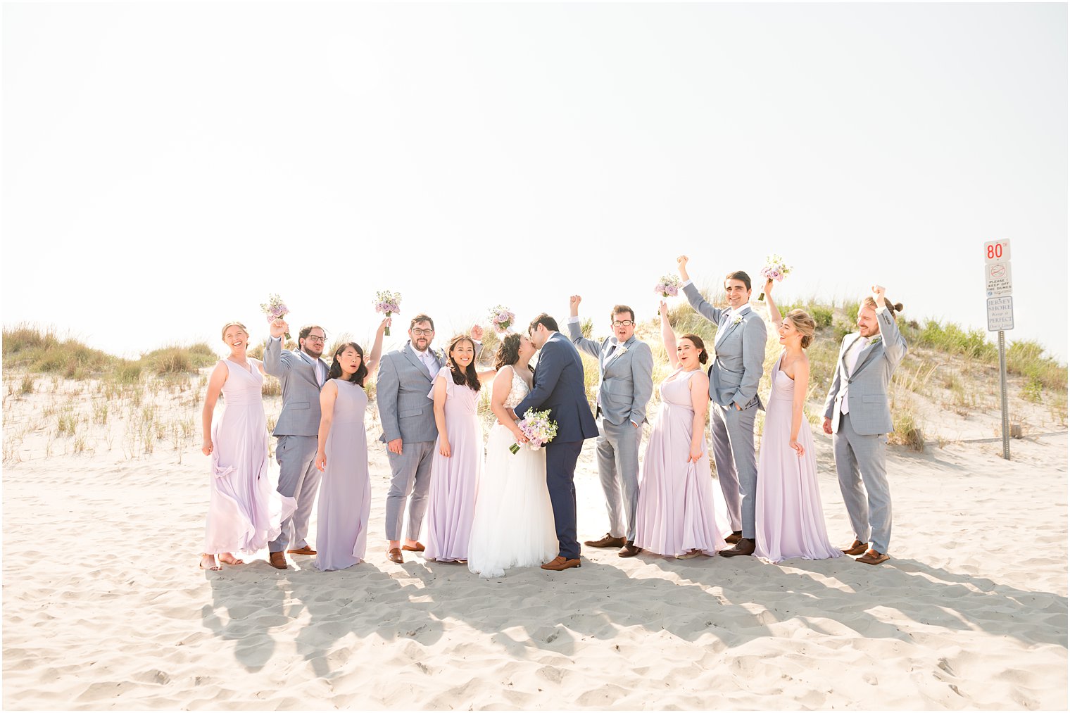 newlyweds kiss while wedding party cheers on Avalon Beach