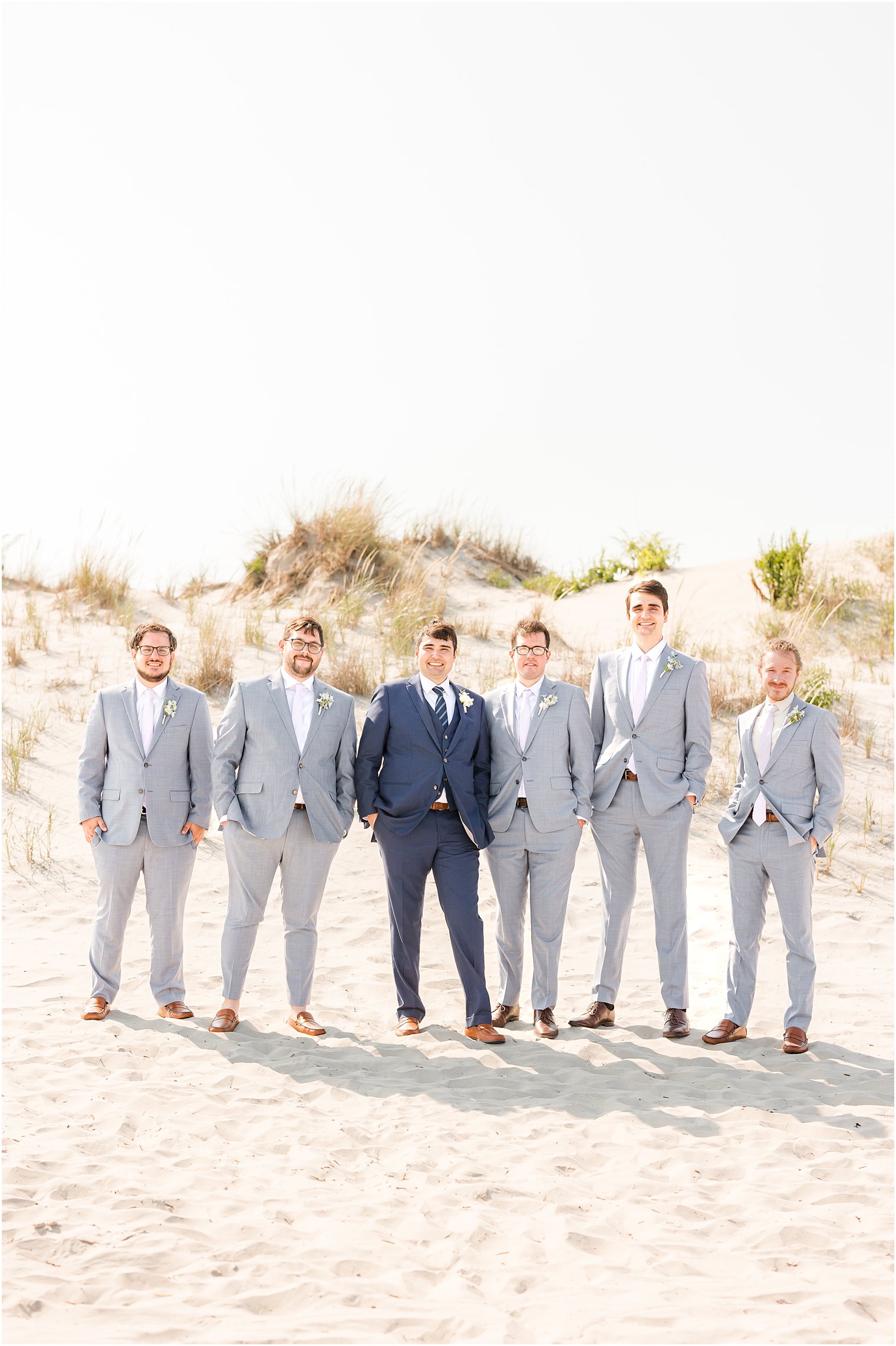 groom stands with groomsmen in grey suits near Icona Winddrift