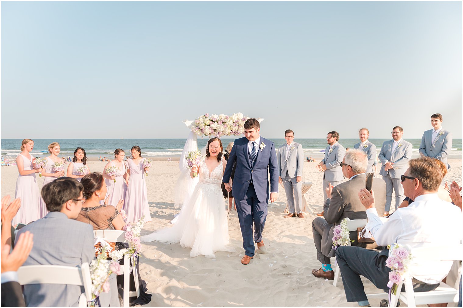 newlyweds walk up aisle cheering after beach wedding ceremony in Avalon NJ